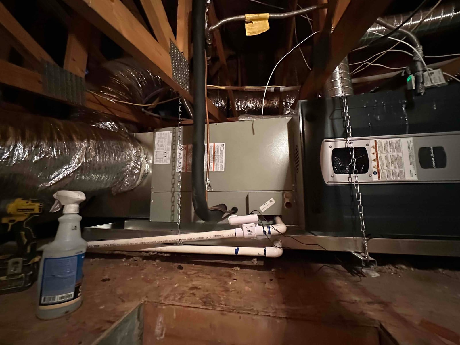 Air handler and furnace installed on a platform in the attic with insulated ductwork and PVC condensate drain piping.