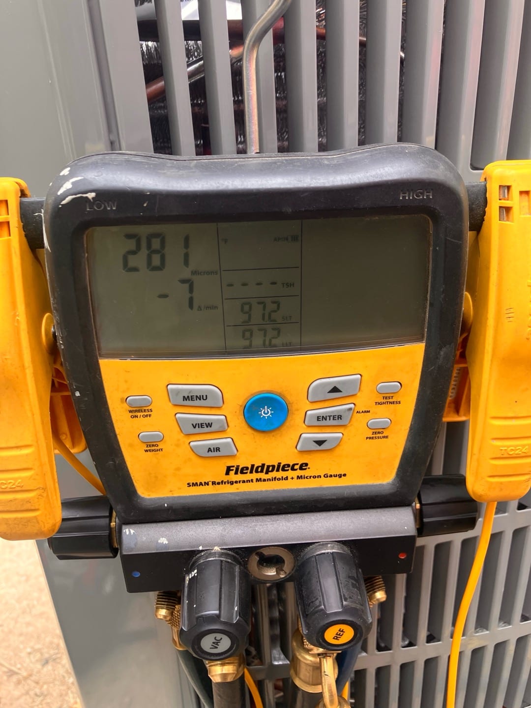 Digital micron gauge on the condenser shows 281 microns during evacuation, confirming a deep vacuum before refrigerant charging.