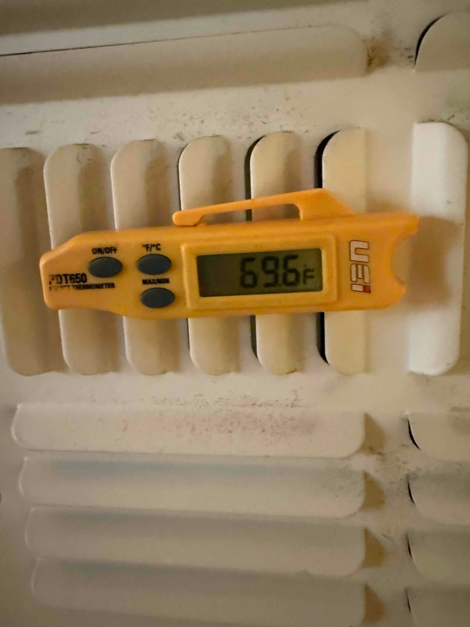 Digital thermometer clipped to a vent grille shows 69.6 °F air temperature at the register.