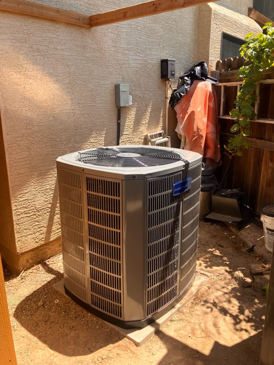 New outdoor condenser set on a level pad beside the house with disconnect mounted and line set penetration sealed.