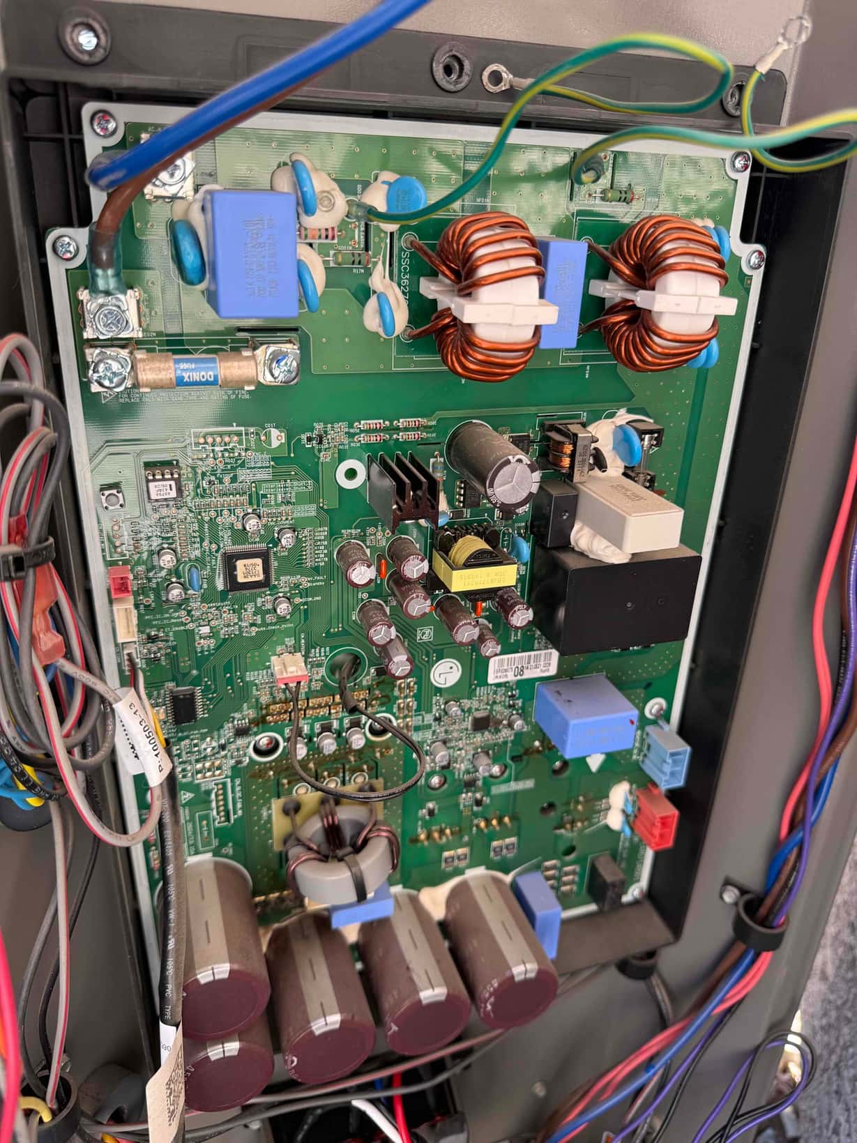 Outdoor inverter control board with inductors, capacitors, relays, and wiring exposed during replacement and testing.