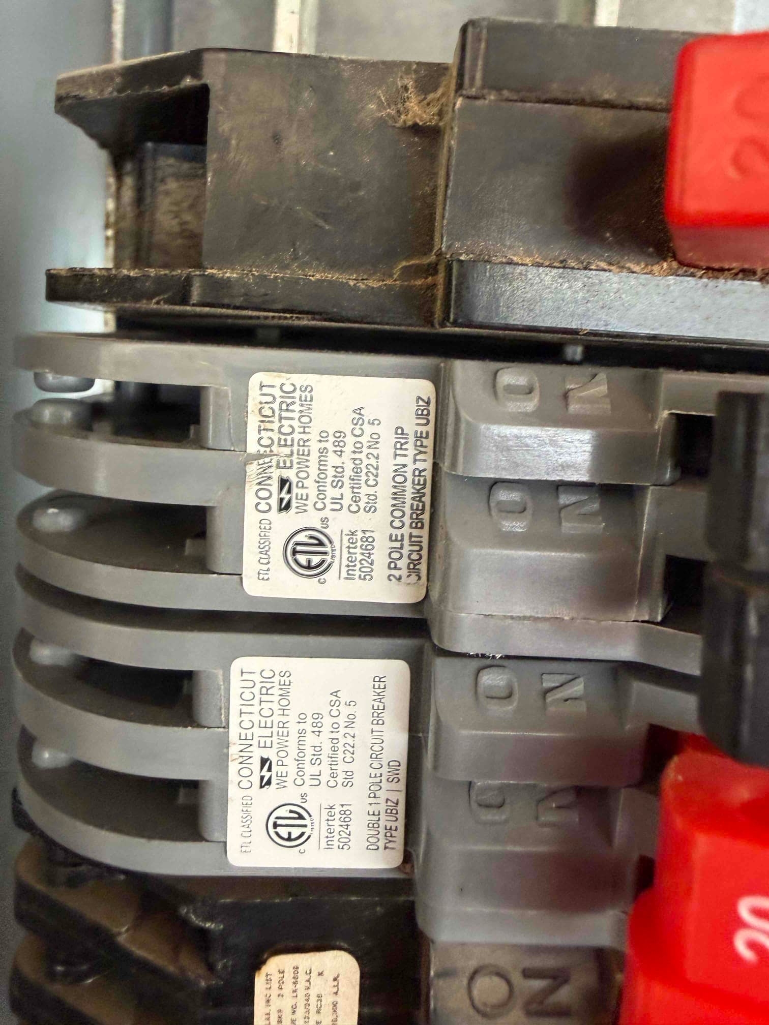 Close-up of labeled circuit breakers in the electrical panel with ON and OFF handles visible for HVAC installation power.