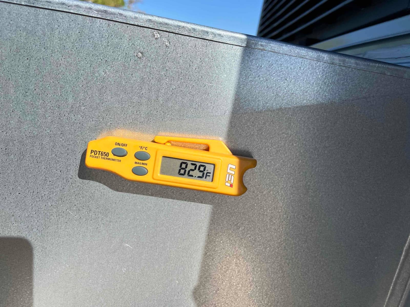Digital thermometer displays 82.9°F while measuring air temperature during commissioning of the newly installed system.