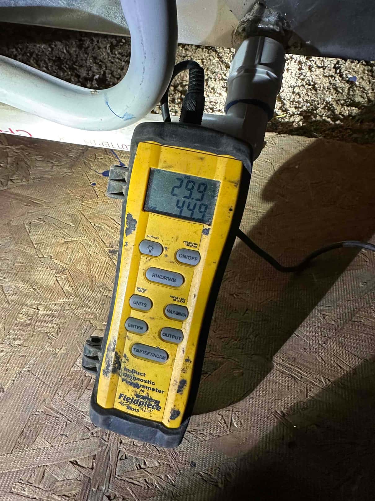 Digital thermometer placed near the air handler shows a 44.8 degree reading during supply air temperature check.