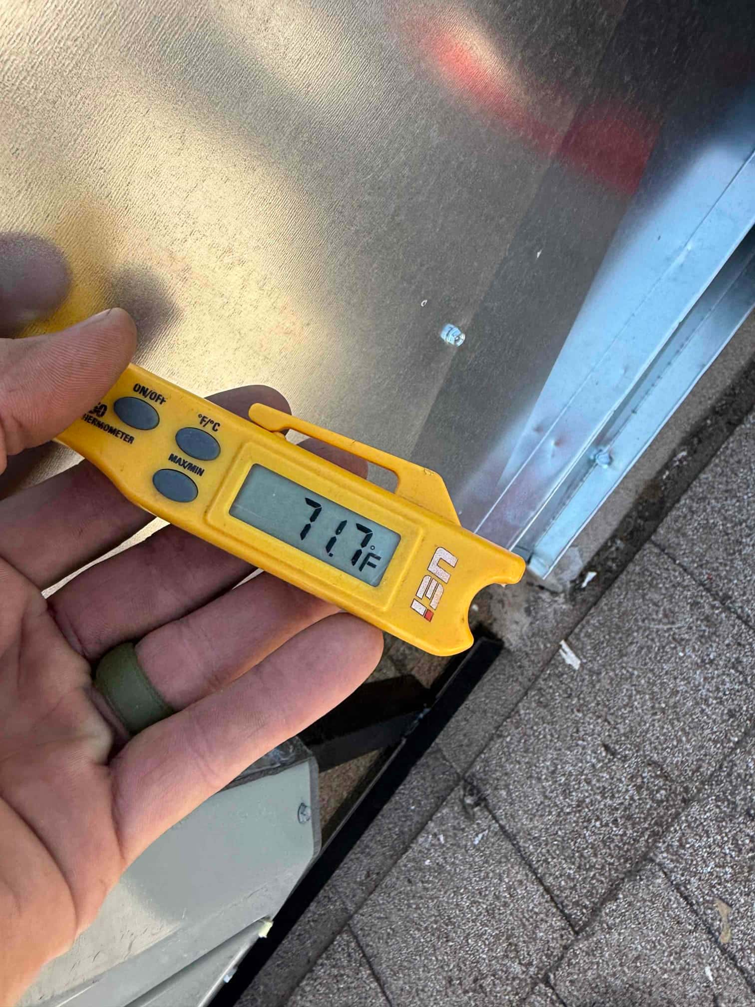 Digital thermometer probe reads 71.7°F while checking air temperature during HVAC commissioning.