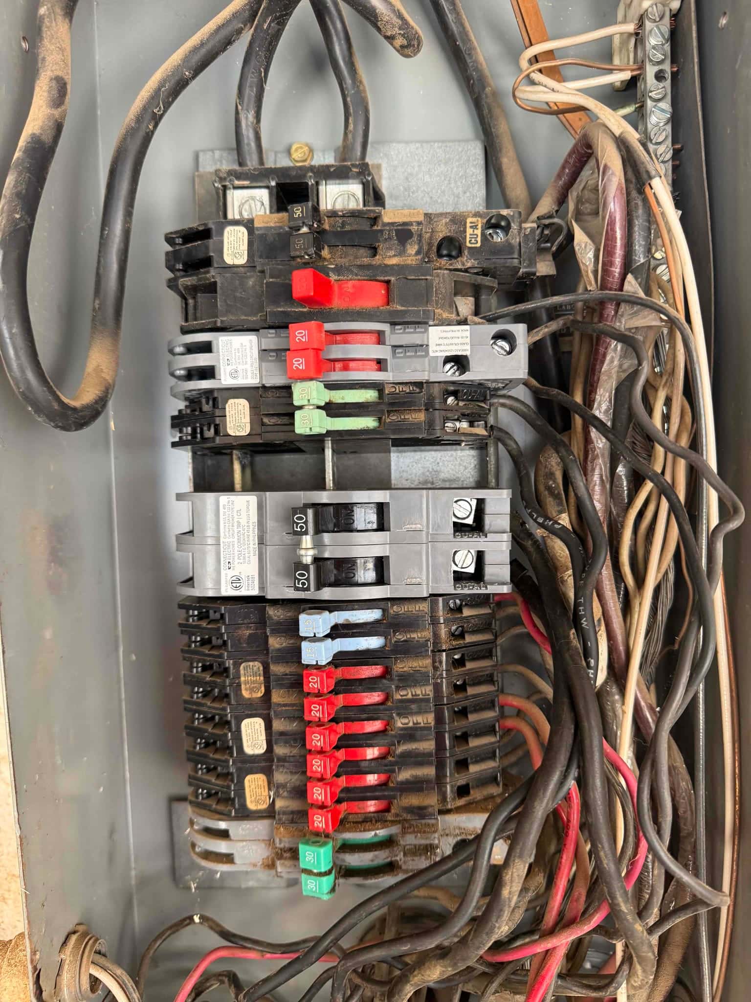 Electrical panel with multiple breakers and wiring visible during HVAC installation, showing dedicated 50-amp double-pole breaker among other circuits.