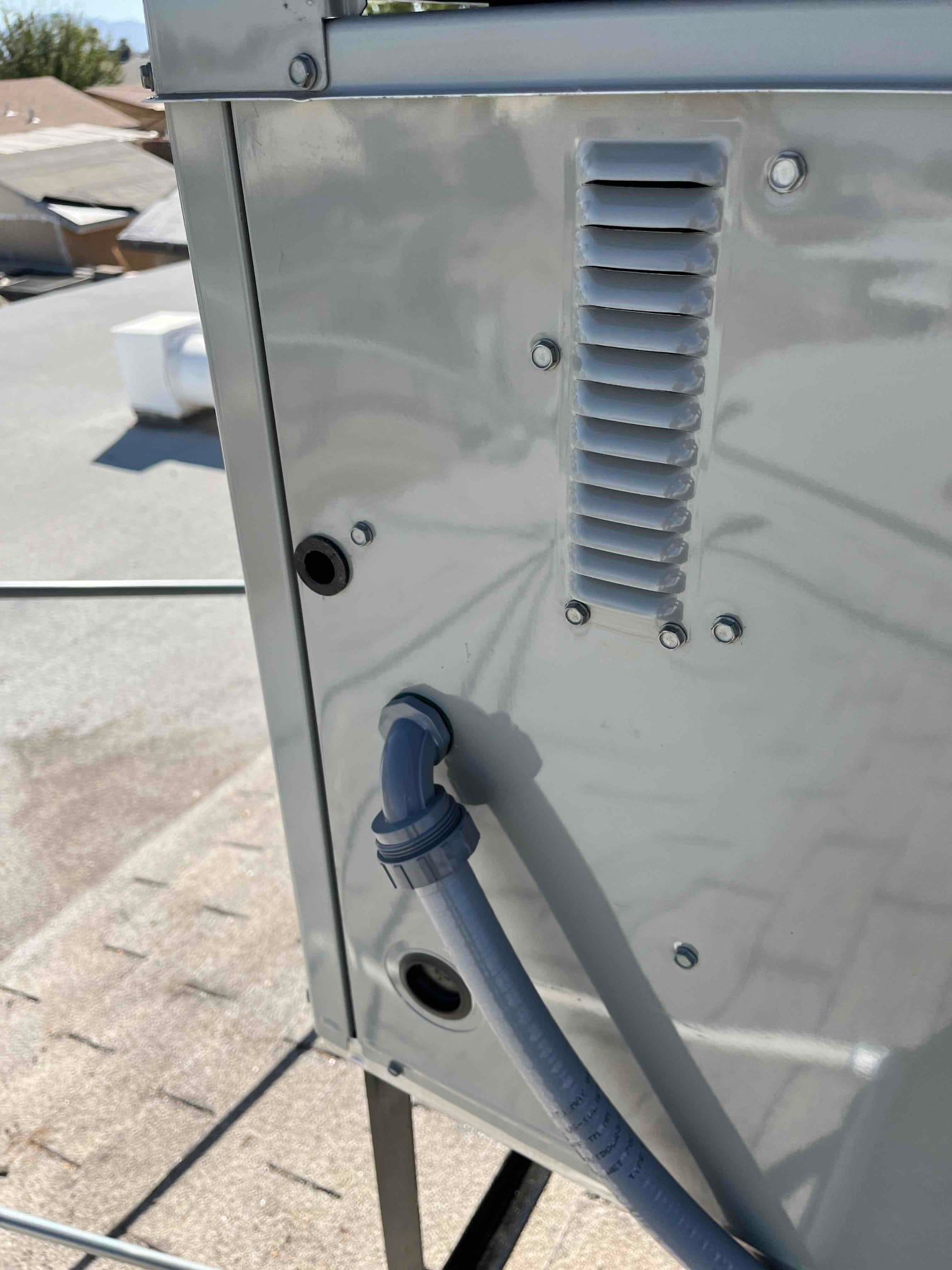 Flexible electrical conduit enters the outdoor unit through a weatherproof connector, with knockouts and louvers visible on the cabinet side.