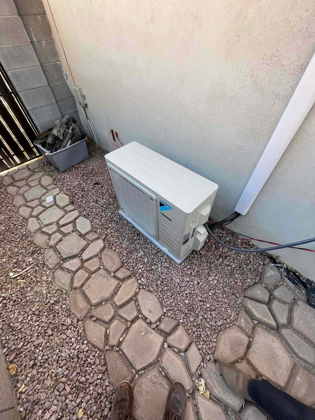 New mini-split outdoor unit set on a level pad with line set cover running up the wall to the indoor unit.