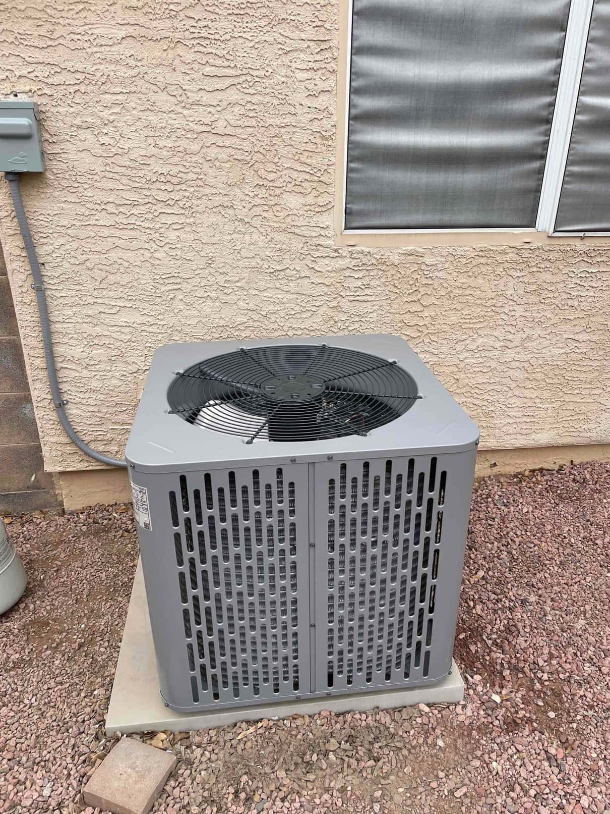 New outdoor condenser set on a level pad with electrical whip to the disconnect and proper clearances around the unit.