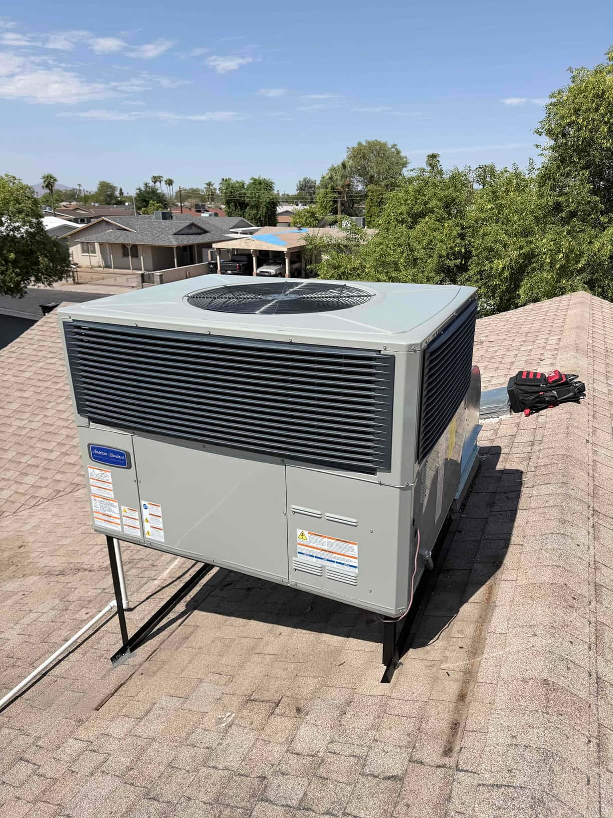 New rooftop packaged HVAC unit mounted on a raised stand with sealed roof penetration and insulated condensate drain line.
