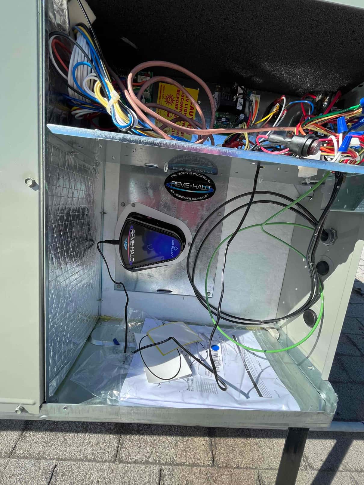 Open air handler cabinet showing wiring, installed air purification module, and internal components during electrical hookup and setup.