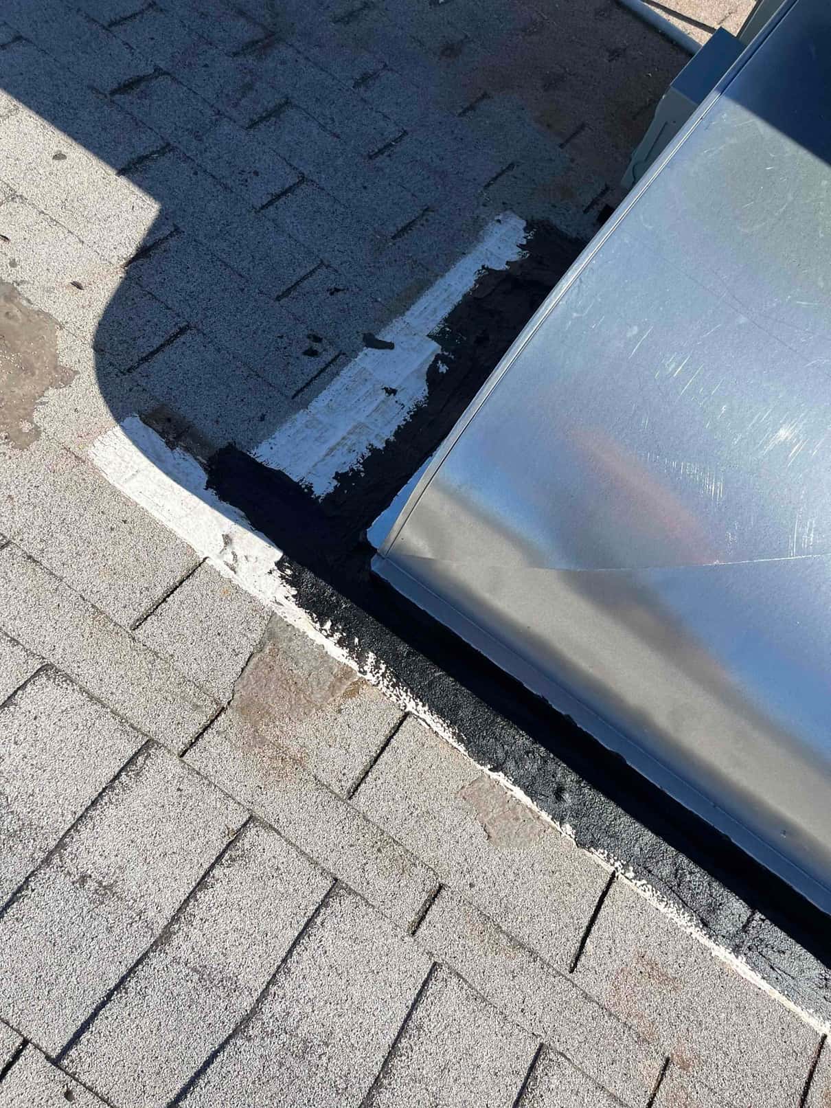 Roof curb flashing and sealant around a newly installed rooftop HVAC unit, showing sealed transitions against asphalt shingles.