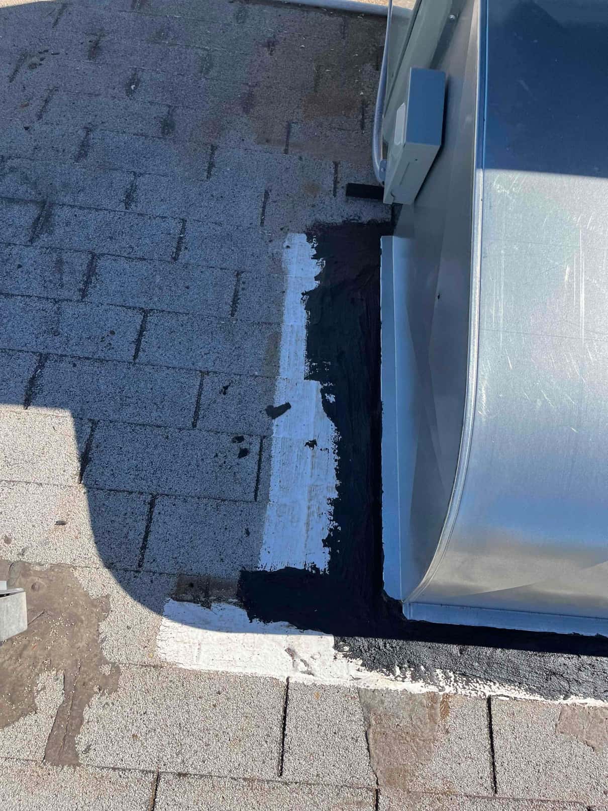 Roof penetration around a metal duct curb is sealed with roofing mastic and coating to ensure a watertight installation.