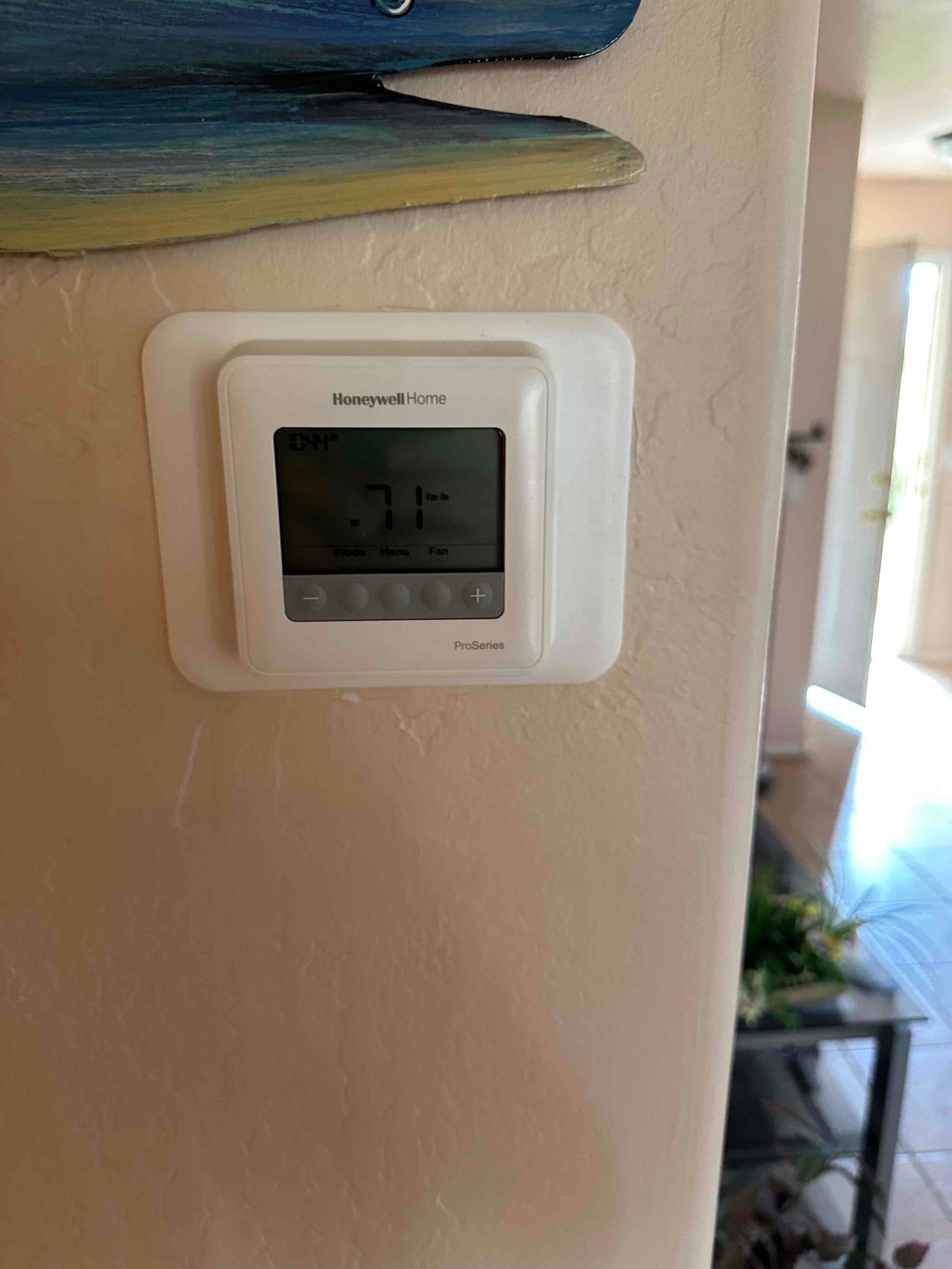 Wall-mounted digital thermostat installed and operating, displaying an indoor temperature of 71 degrees with system controls visible.