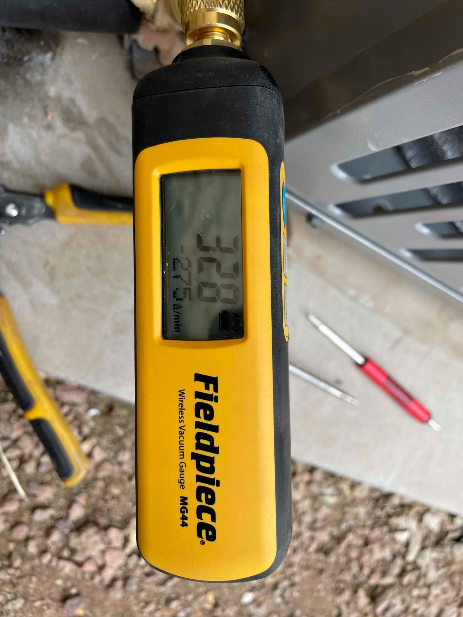 Wireless vacuum gauge connected at the service port displays 320 microns, confirming a deep evacuation before refrigerant charging.