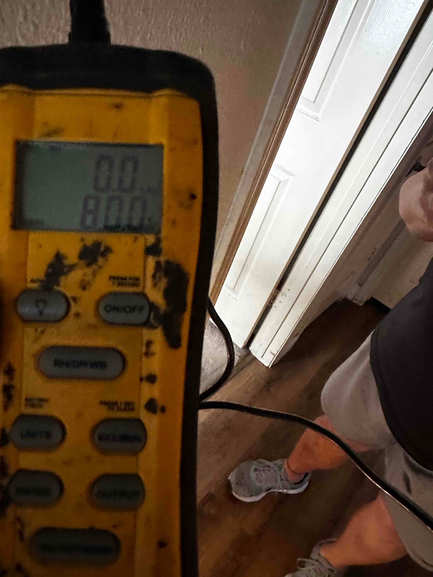 Clamp meter displays 0.0 amps while measuring current on a wire during HVAC installation commissioning inside the home.