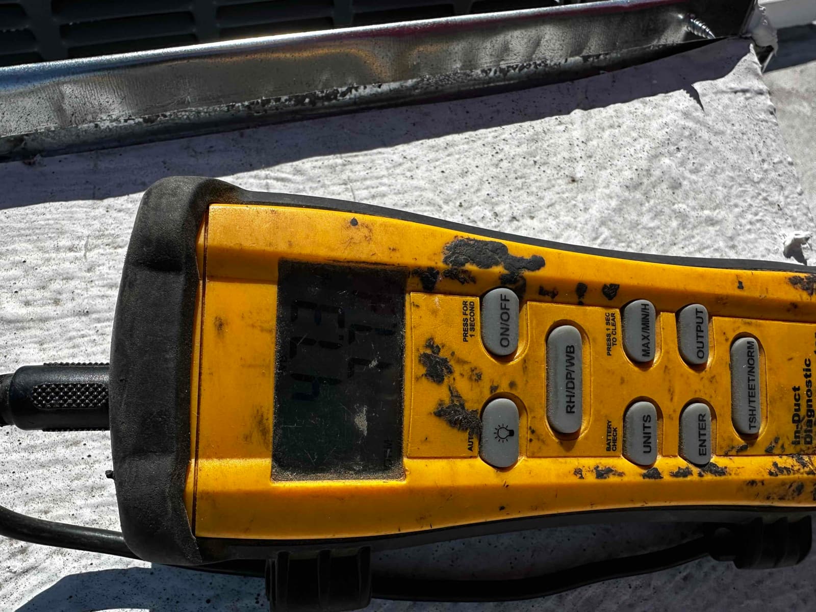 Digital thermometer instrument on the job site showing a temperature reading of 47.3°F during air-side testing.