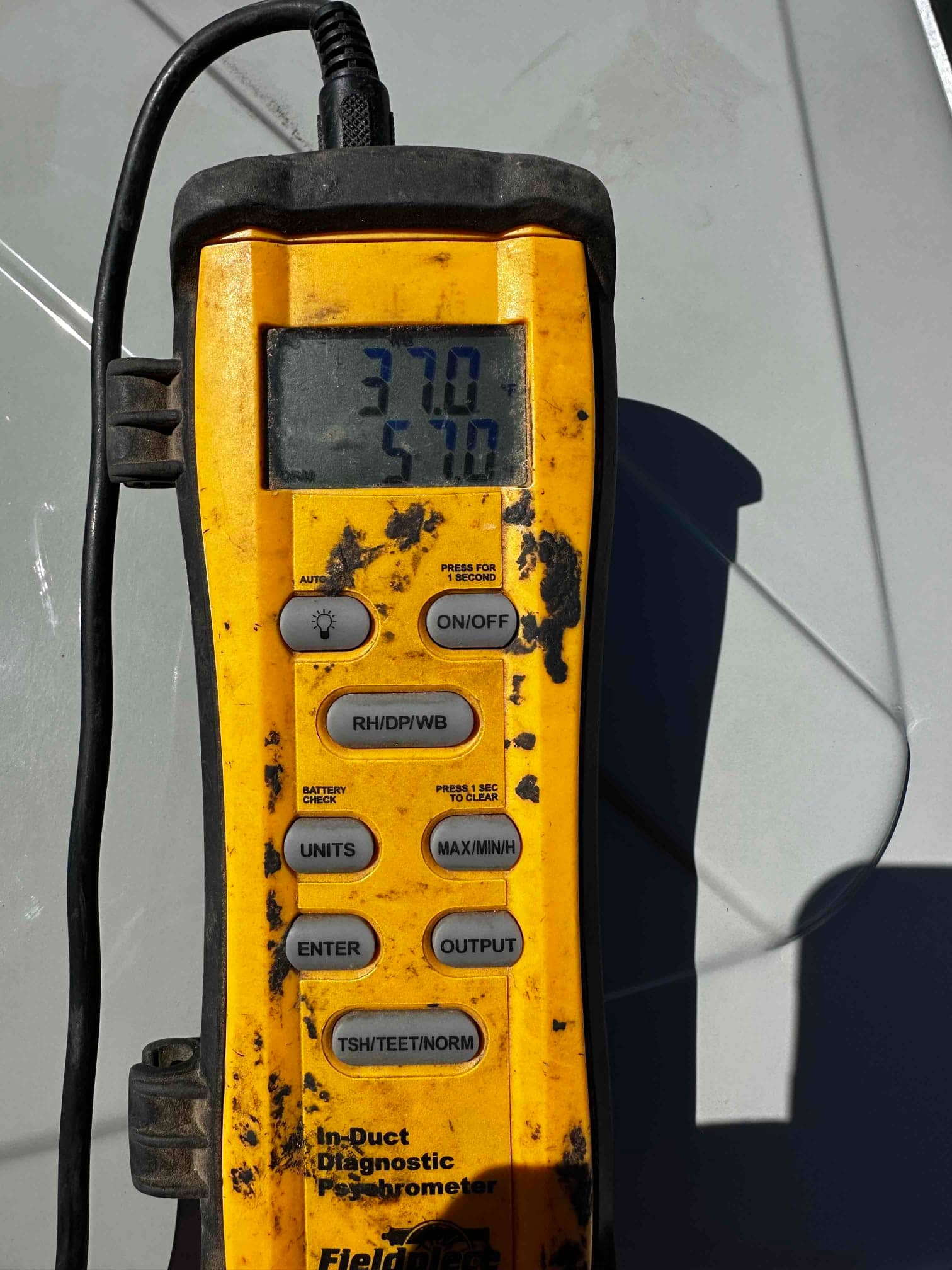 Digital thermometer shows 37.0 and 57.0 degrees during air temperature checks on the newly installed system.