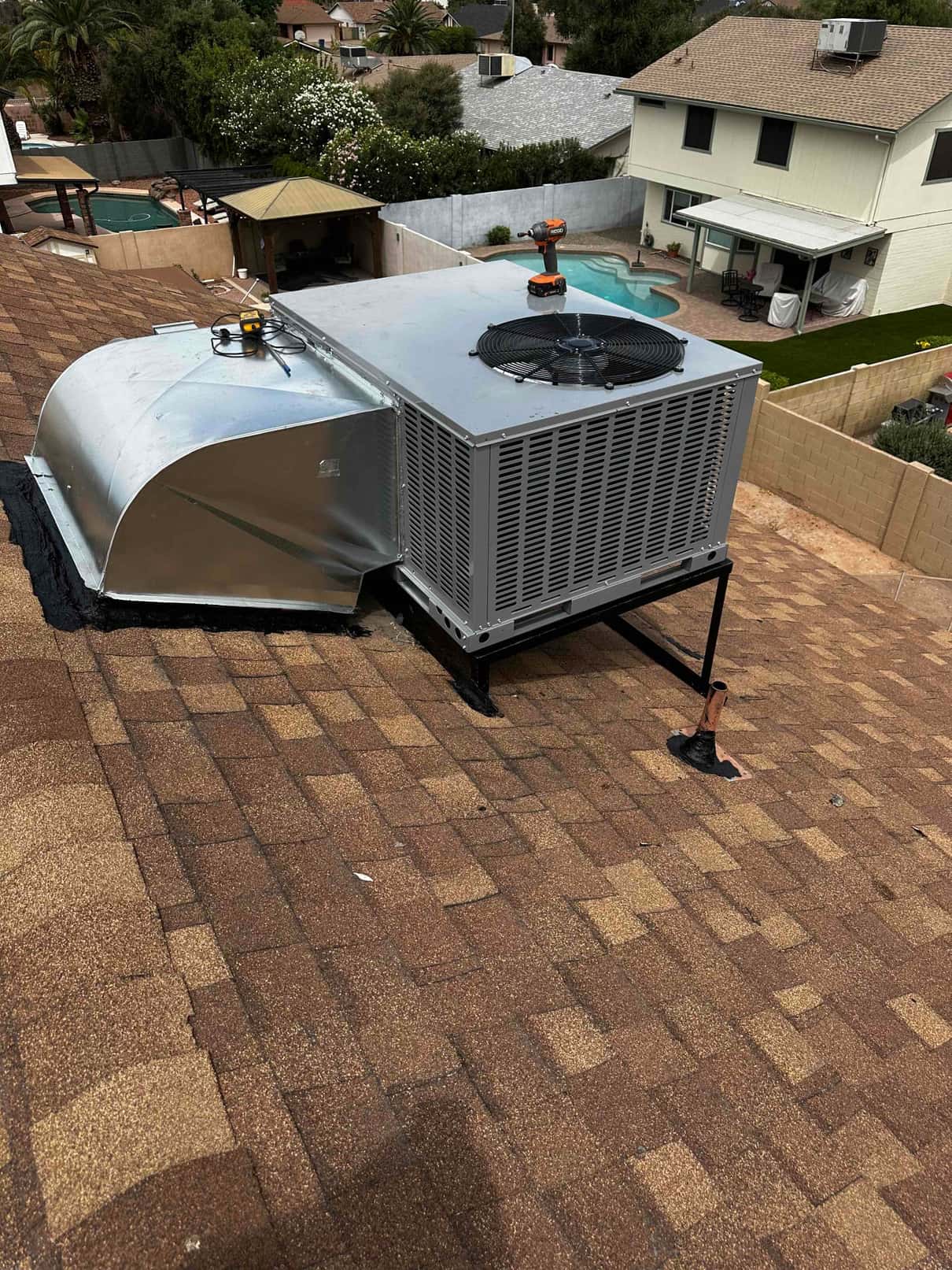 New rooftop package unit installed on a stand with curb transition ductwork and sealed roof penetrations visible.