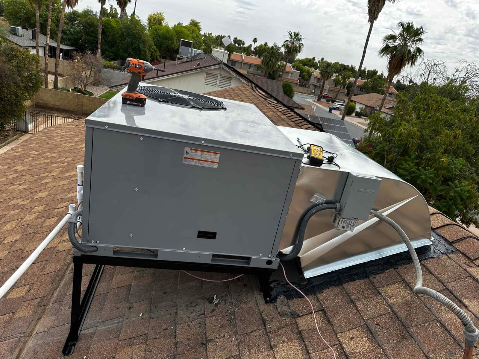 New rooftop package unit set on a metal stand with sealed curb, electrical disconnect, and condensate drain piping routed.