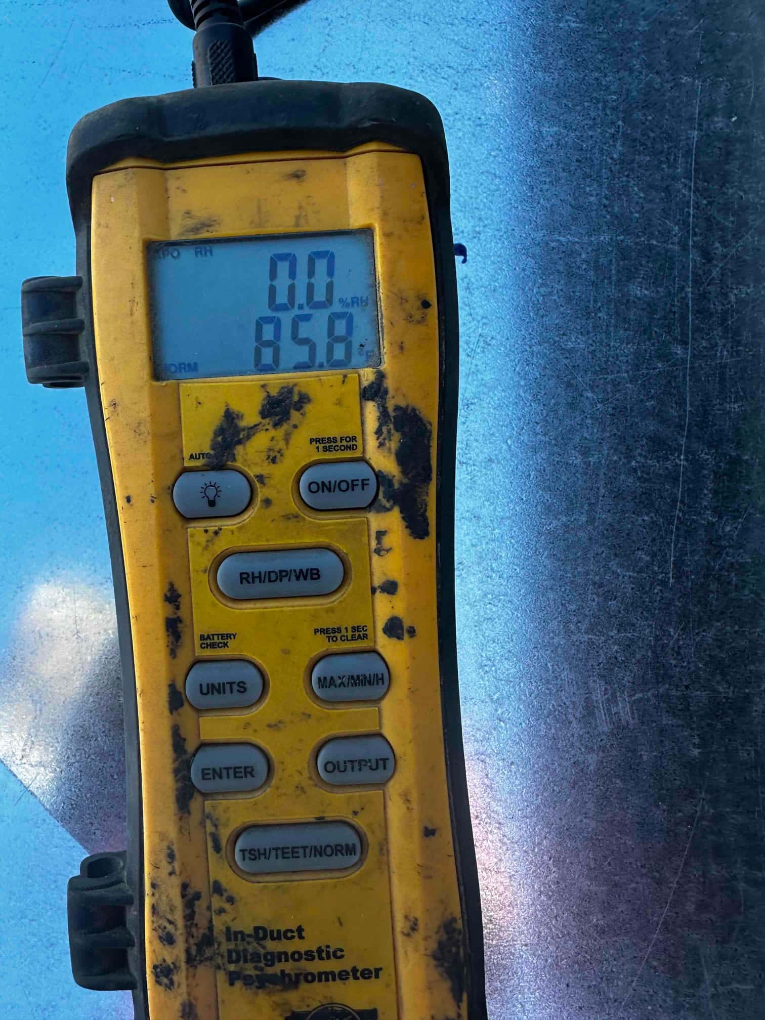 Digital thermo-hygrometer shows 85.8 degrees on the display while checking air conditions at the ductwork.