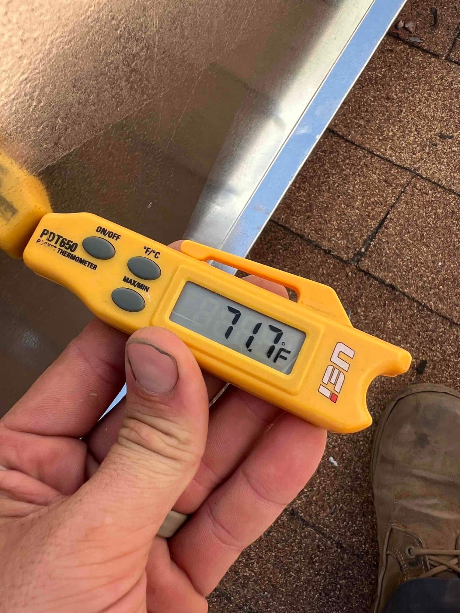 Digital thermometer displays 71.7°F while checking air temperature during commissioning of the newly installed HVAC system.