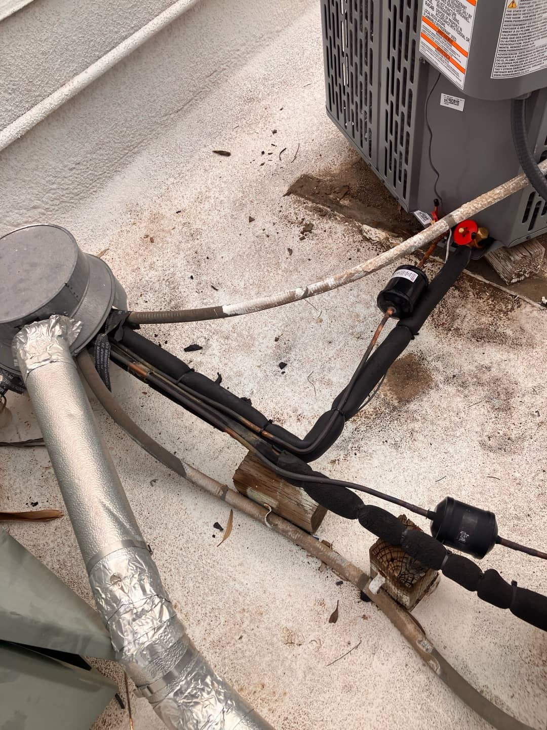 New outdoor condenser connections with insulated refrigerant lines, filter drier, and line set supported on blocks at the installation site.