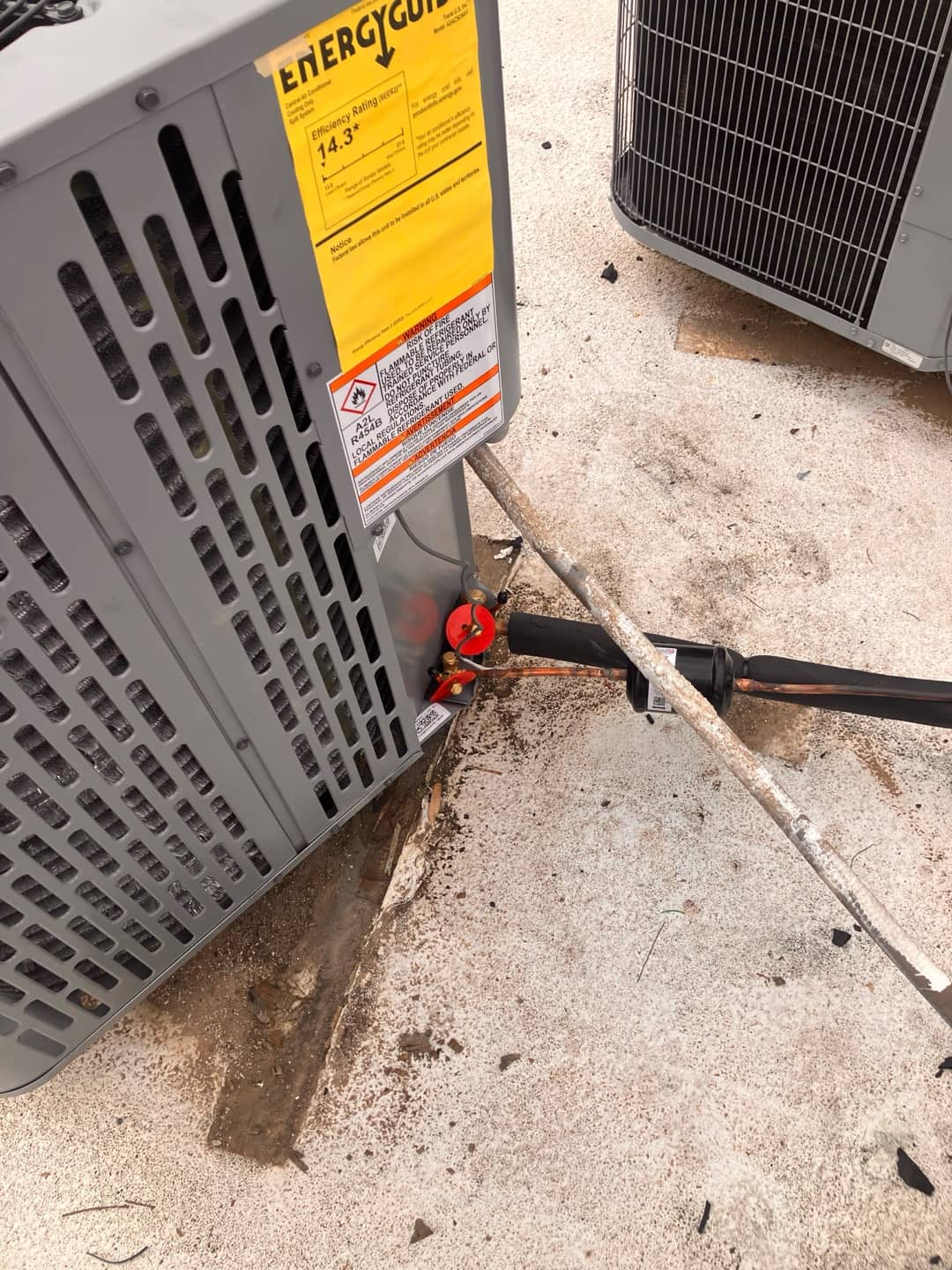 New outdoor condenser set on pad with insulated refrigerant line set connected and service valves capped.