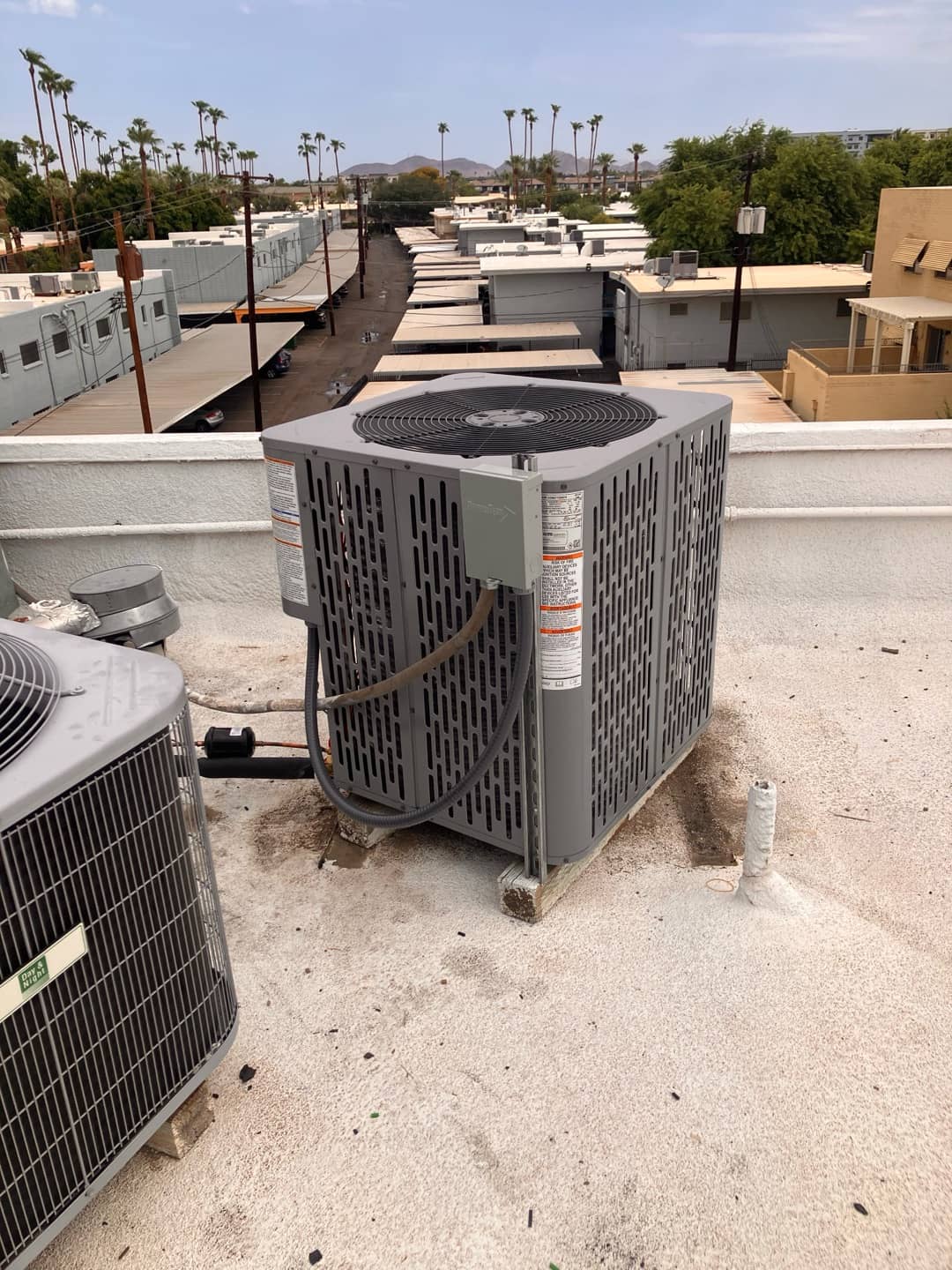 New rooftop condenser set on supports with electrical disconnect mounted and insulated line set routed to the unit.