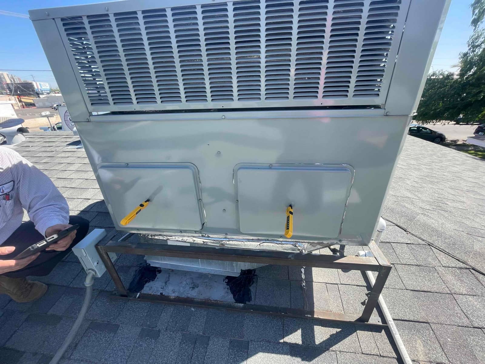 New rooftop package unit set on a metal stand with sealed roof curb and nearby electrical disconnect visible.