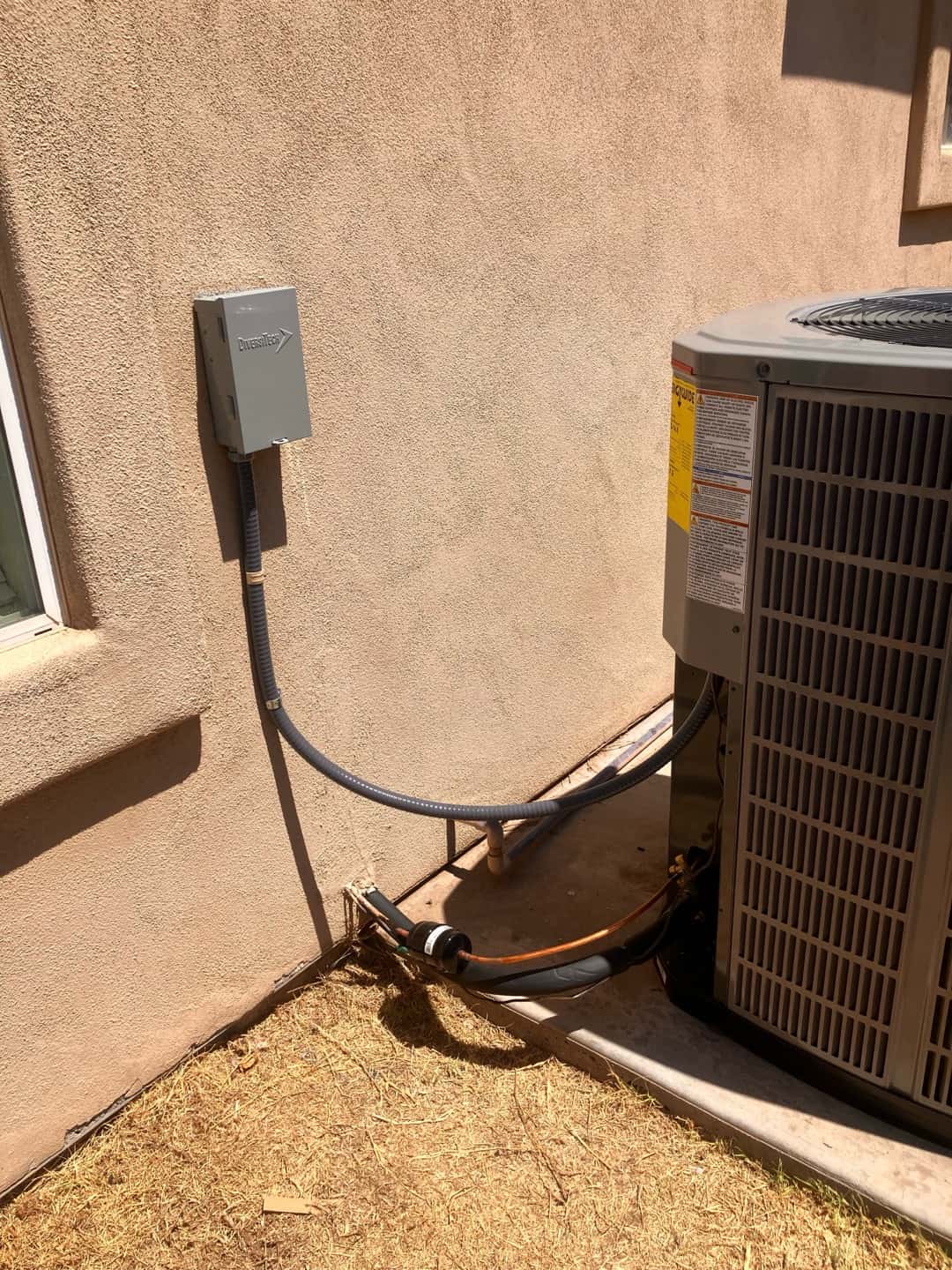 Outdoor heat pump condenser set on a pad with new disconnect, armored whip, insulated line set, and sealed wall penetration.