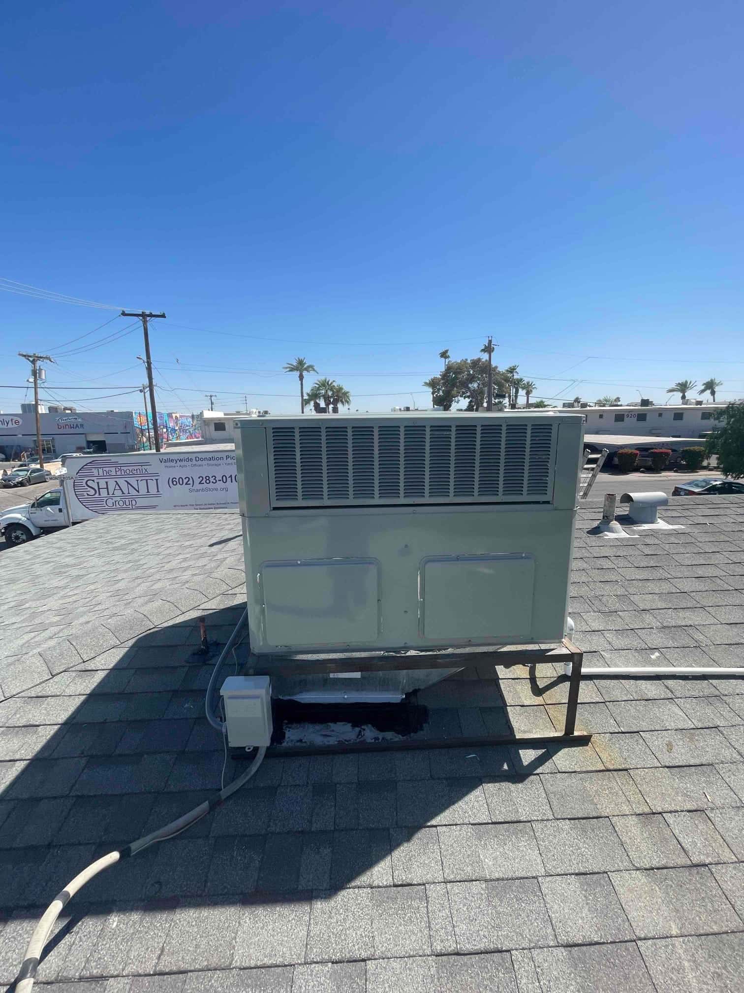 Rooftop package HVAC unit installed on a raised stand with electrical disconnect and sealed roof penetration visible.