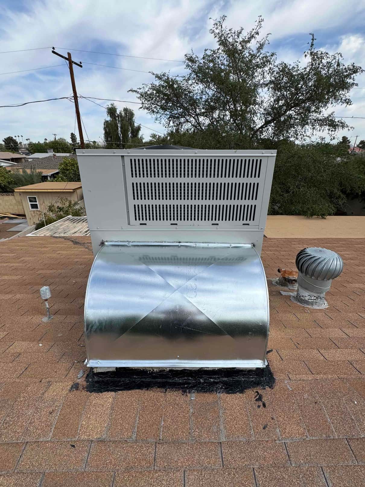 Rooftop package unit with newly installed sheet-metal curb and sealed roof penetration, shown from the discharge side.