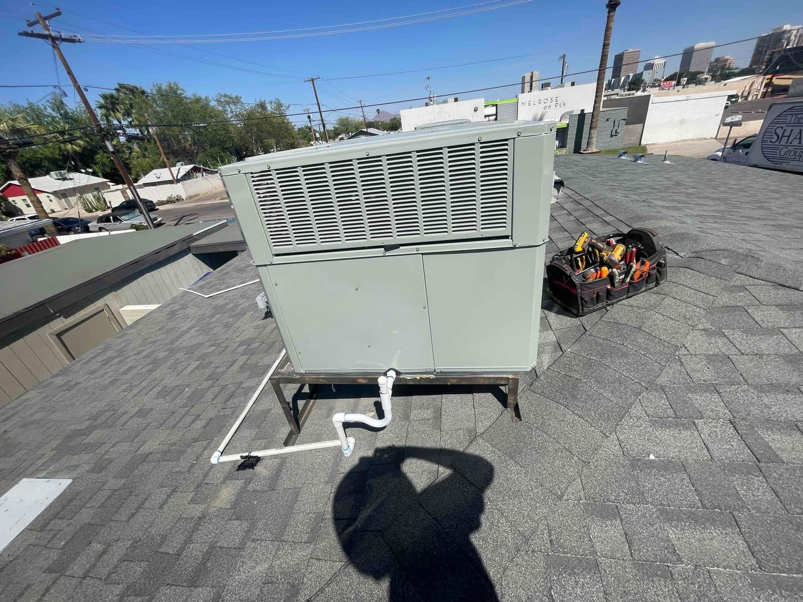 Rooftop packaged HVAC unit installed on a metal stand with newly plumbed condensate drain and tools staged nearby.
