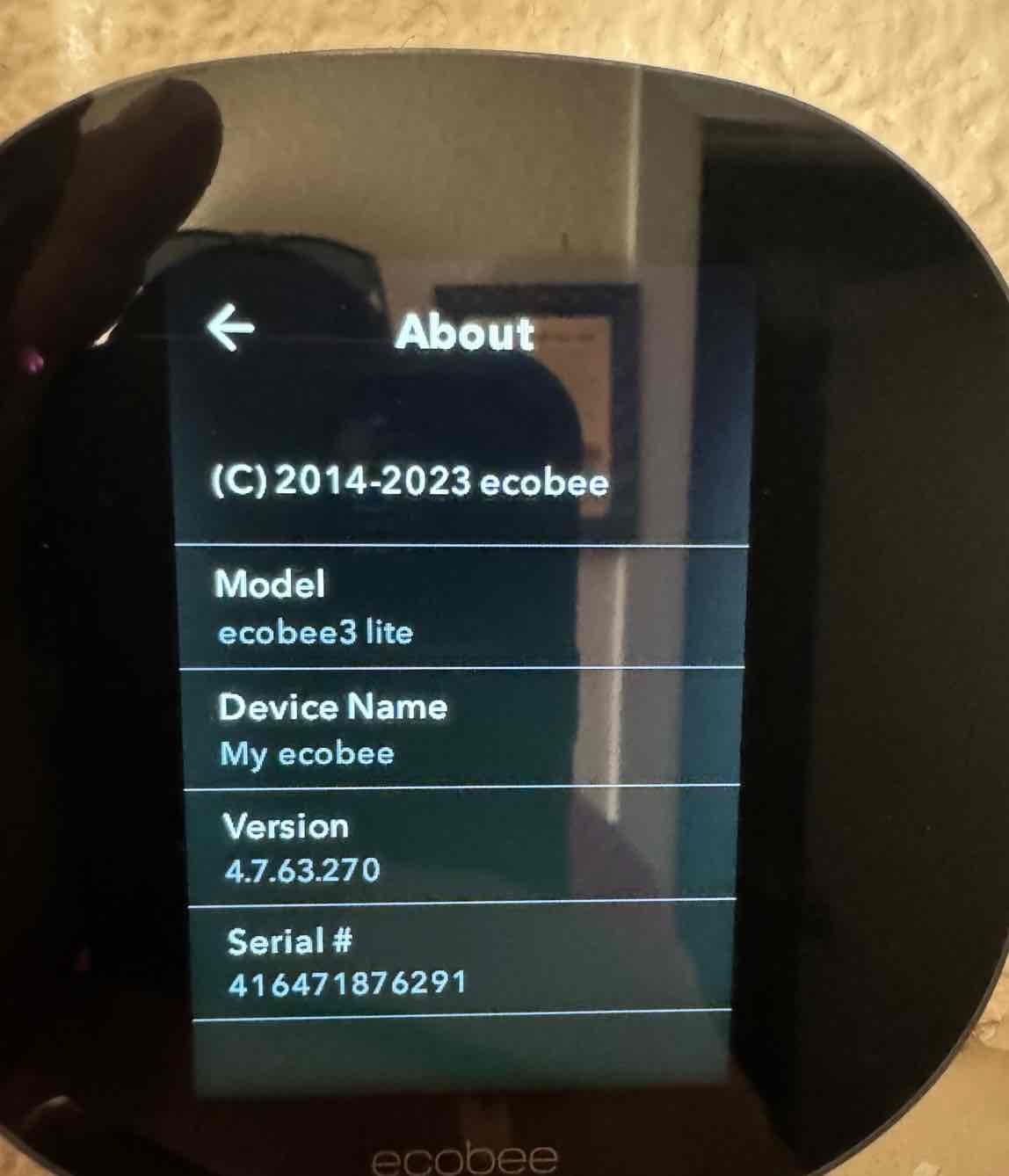 Smart thermostat display shows device information screen after installation, confirming setup and system integration at the indoor control location.