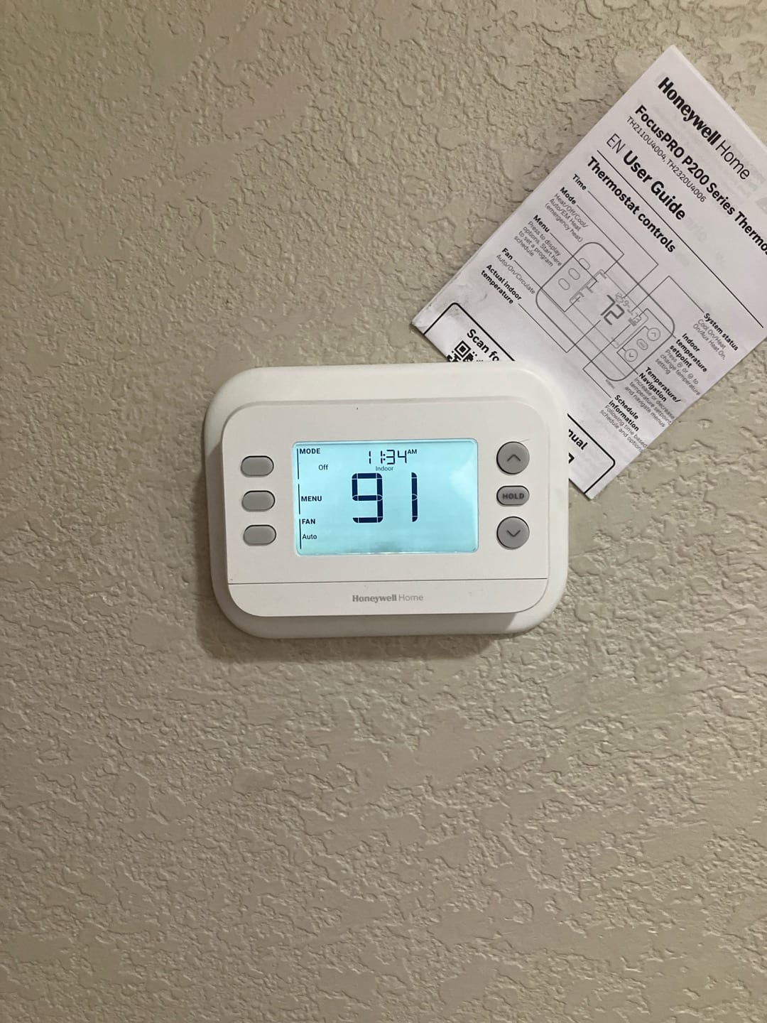 Wall-mounted digital thermostat installed and powered, displaying indoor temperature and system mode on the screen.