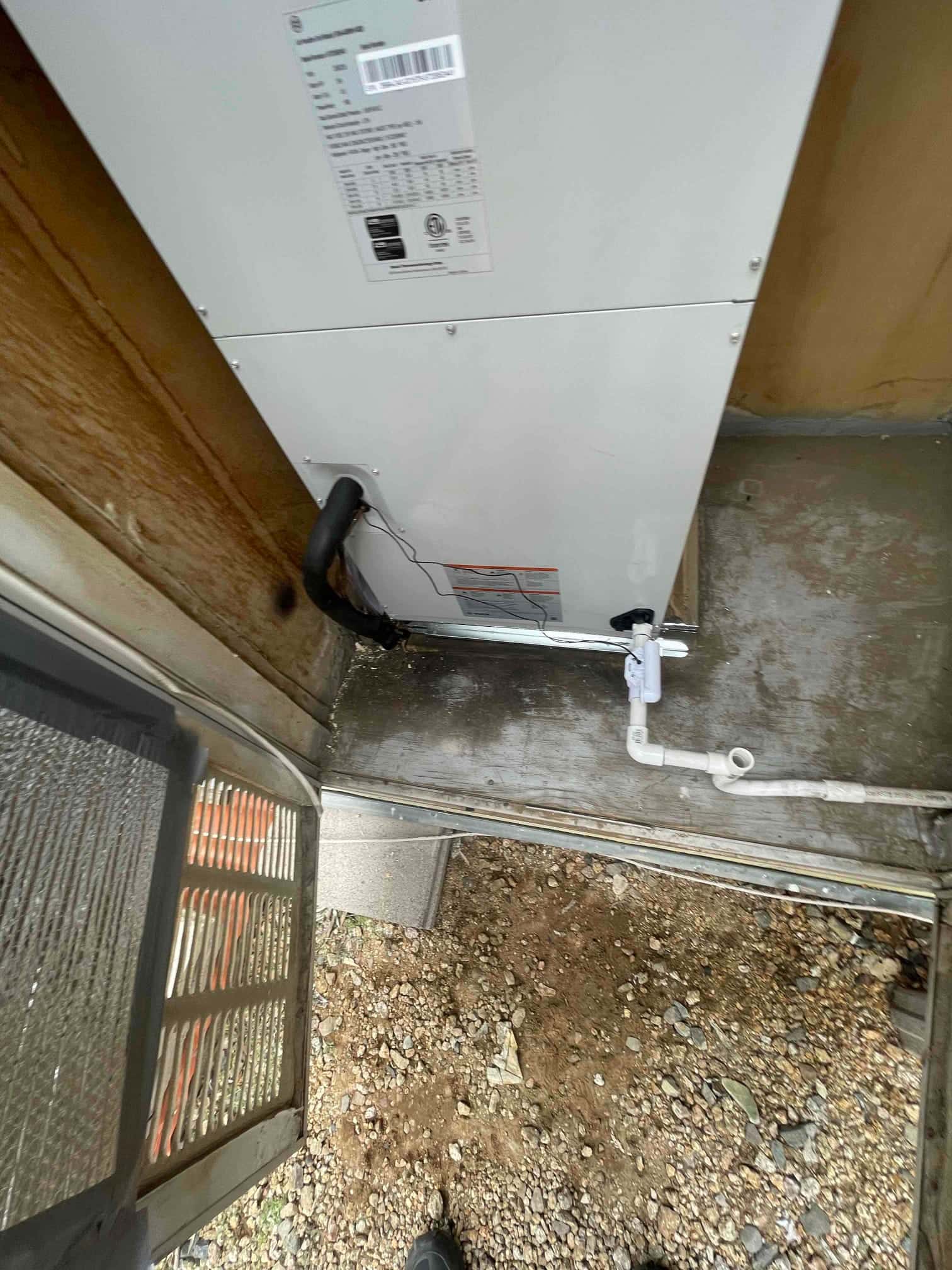 Air handler set in place with insulated refrigerant line and new condensate drain assembly routed to the side.