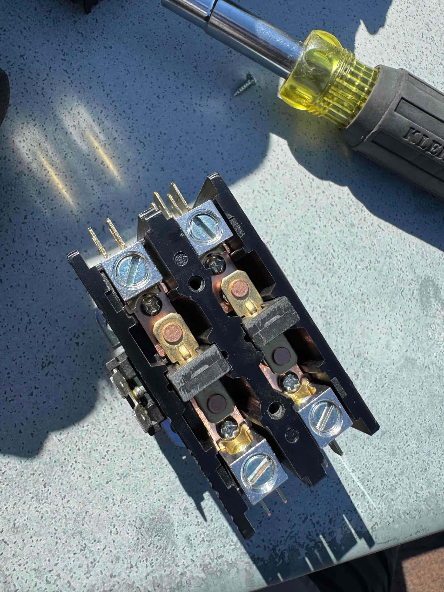 Close-up of a two-pole contactor showing clean terminals, contact points, and coil connections on a work surface.