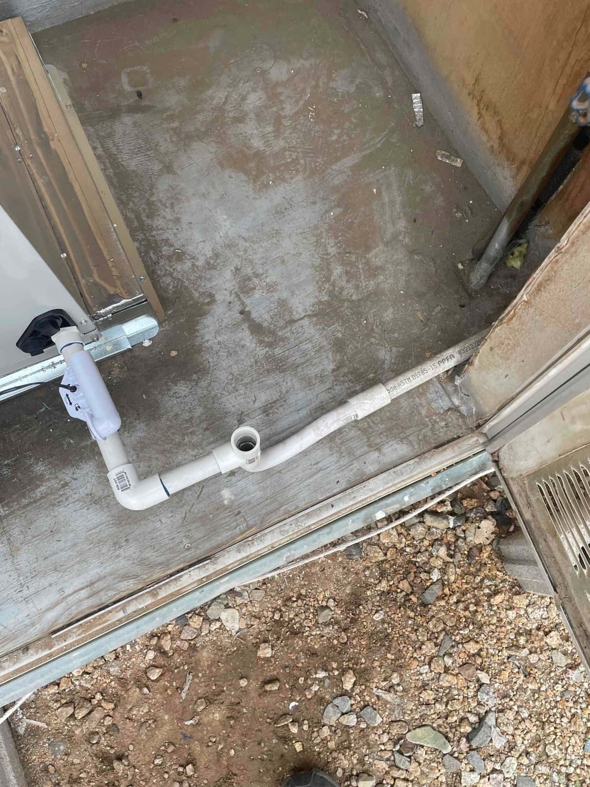 Condensate drain line with cleanout tee and trap routed from the air handler to the exterior penetration.