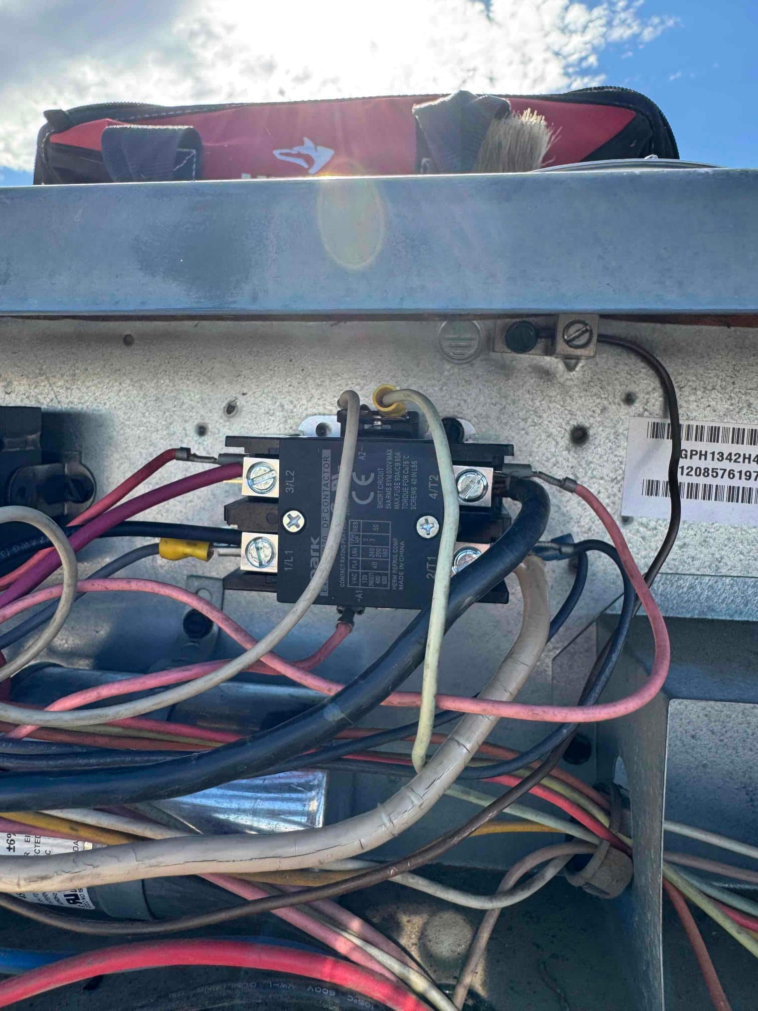 Contactor installed in the condenser control compartment with multiple wires connected and surrounding components visible inside the unit.