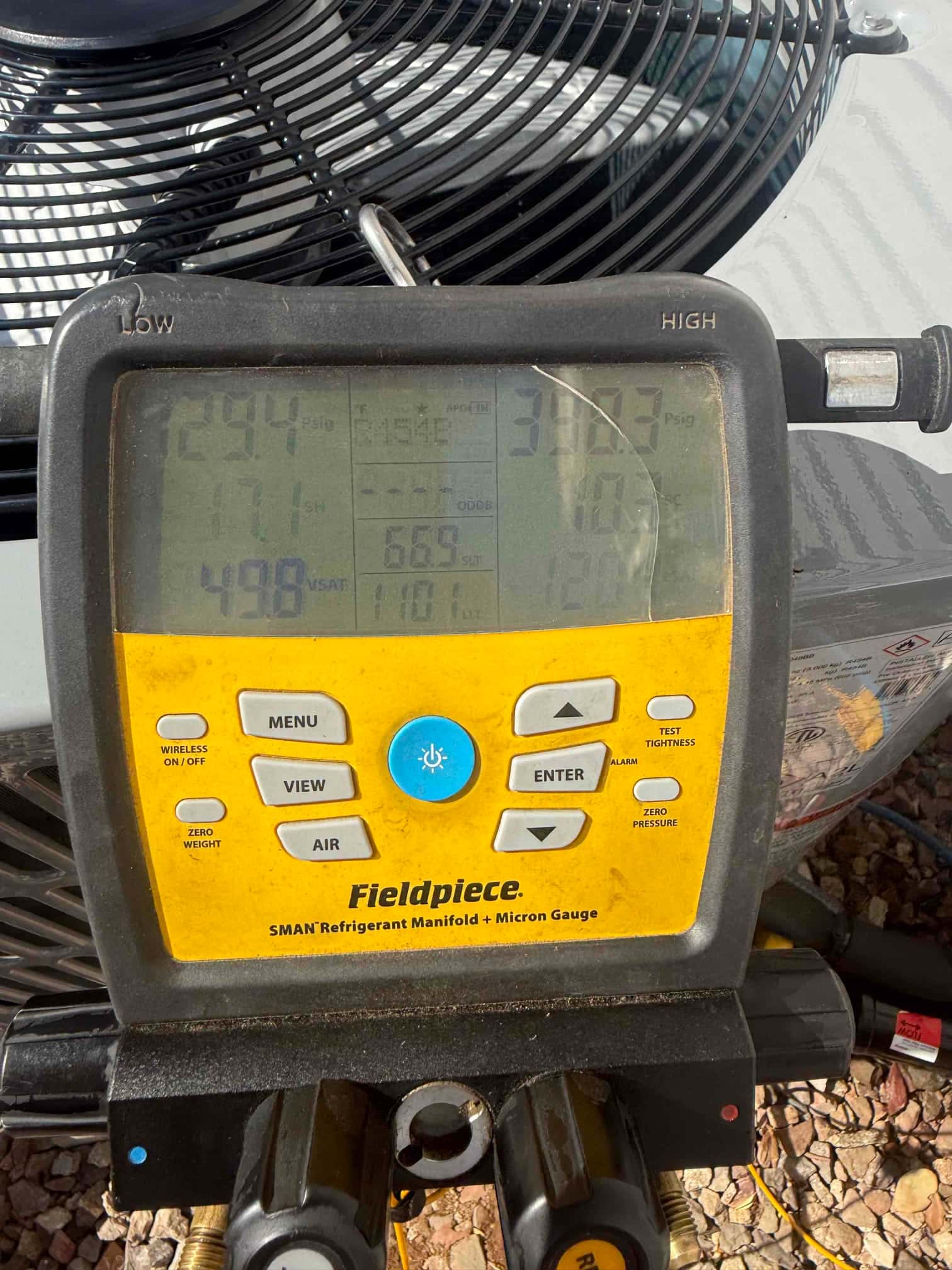 Digital manifold connected to the outdoor unit shows operating refrigerant pressures with distinct low and high side readings during commissioning.