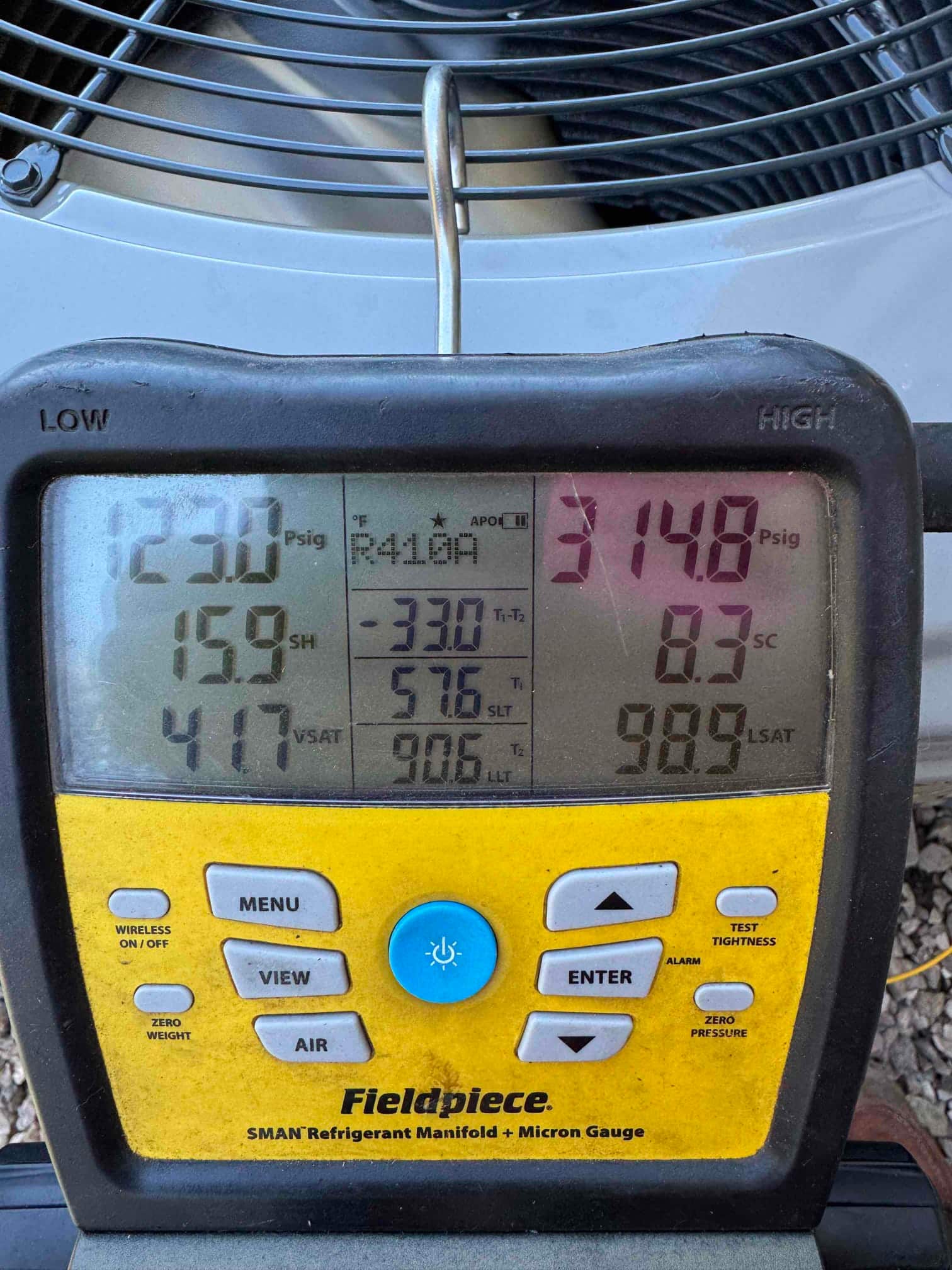 Digital manifold shows system operating pressures with low side at 123 psig and high side at 314.8 psig during commissioning.