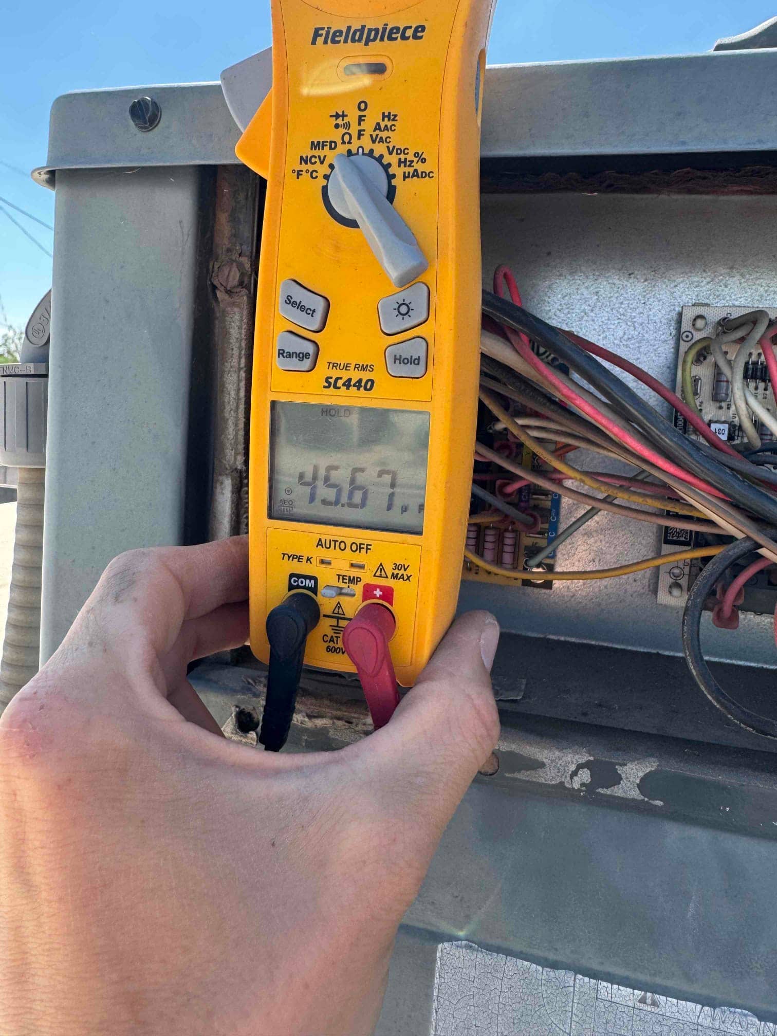 Digital multimeter displays 456.7 µF while measuring capacitance on the outdoor condenser wiring inside the electrical compartment.
