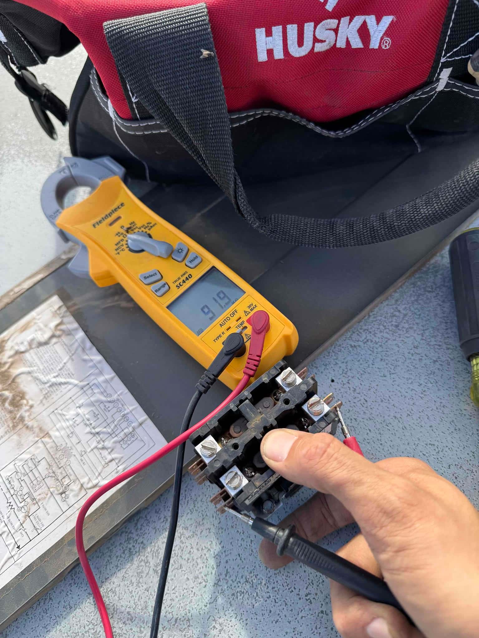 Digital multimeter measures 9.19 V across the contactor terminals while the component is held during testing.