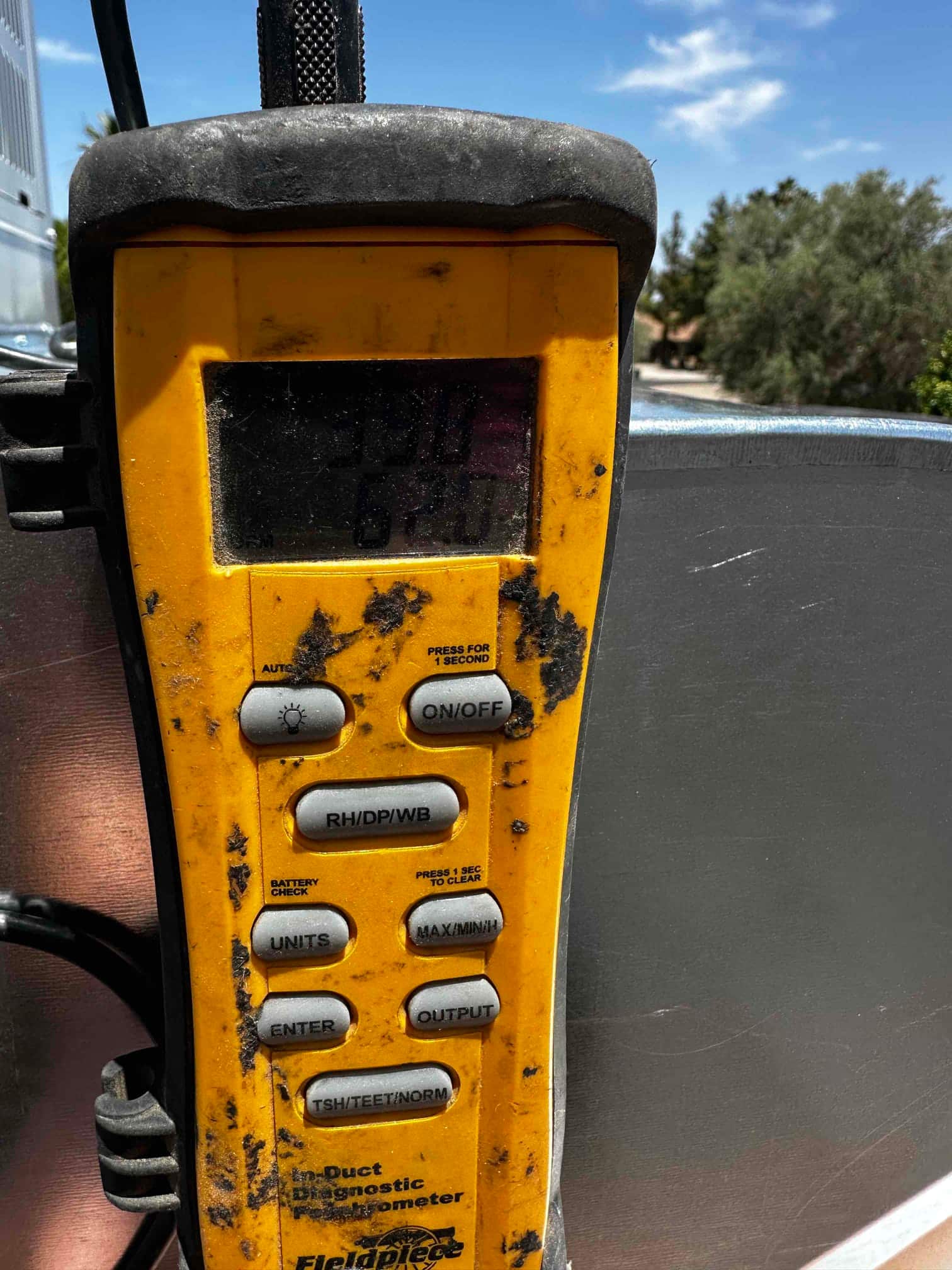 Digital psychrometer used for air measurements during commissioning, with display partially visible and control buttons labeled for humidity and temperature functions.
