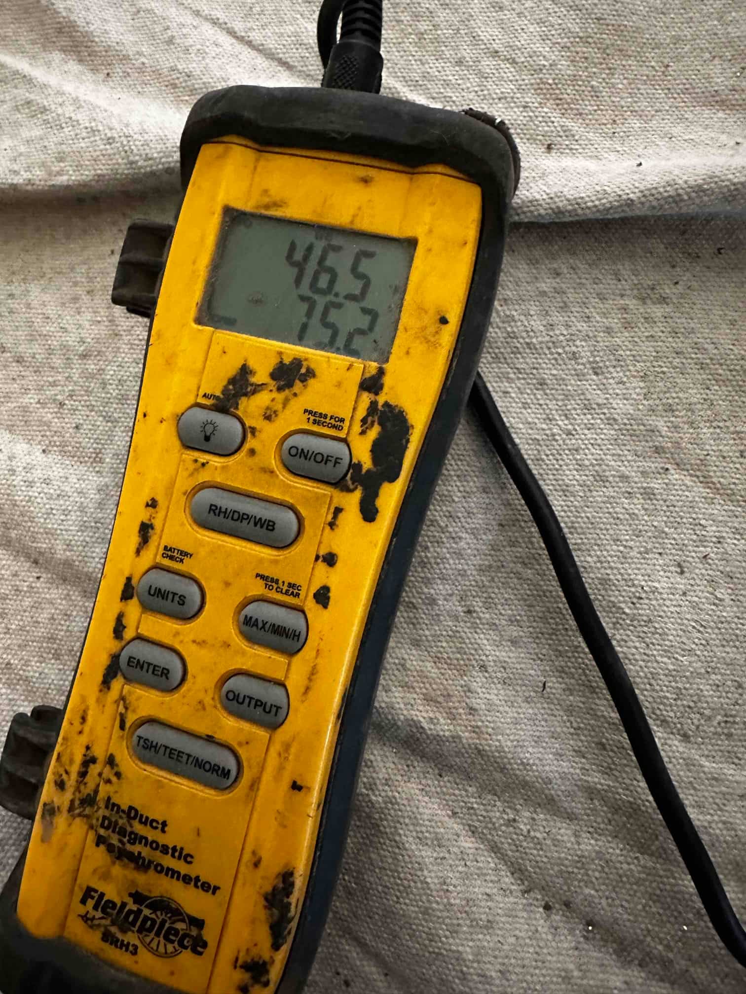 Digital thermometer displays 46.5°F and 75.2°F readings during air temperature checks on the newly installed system.