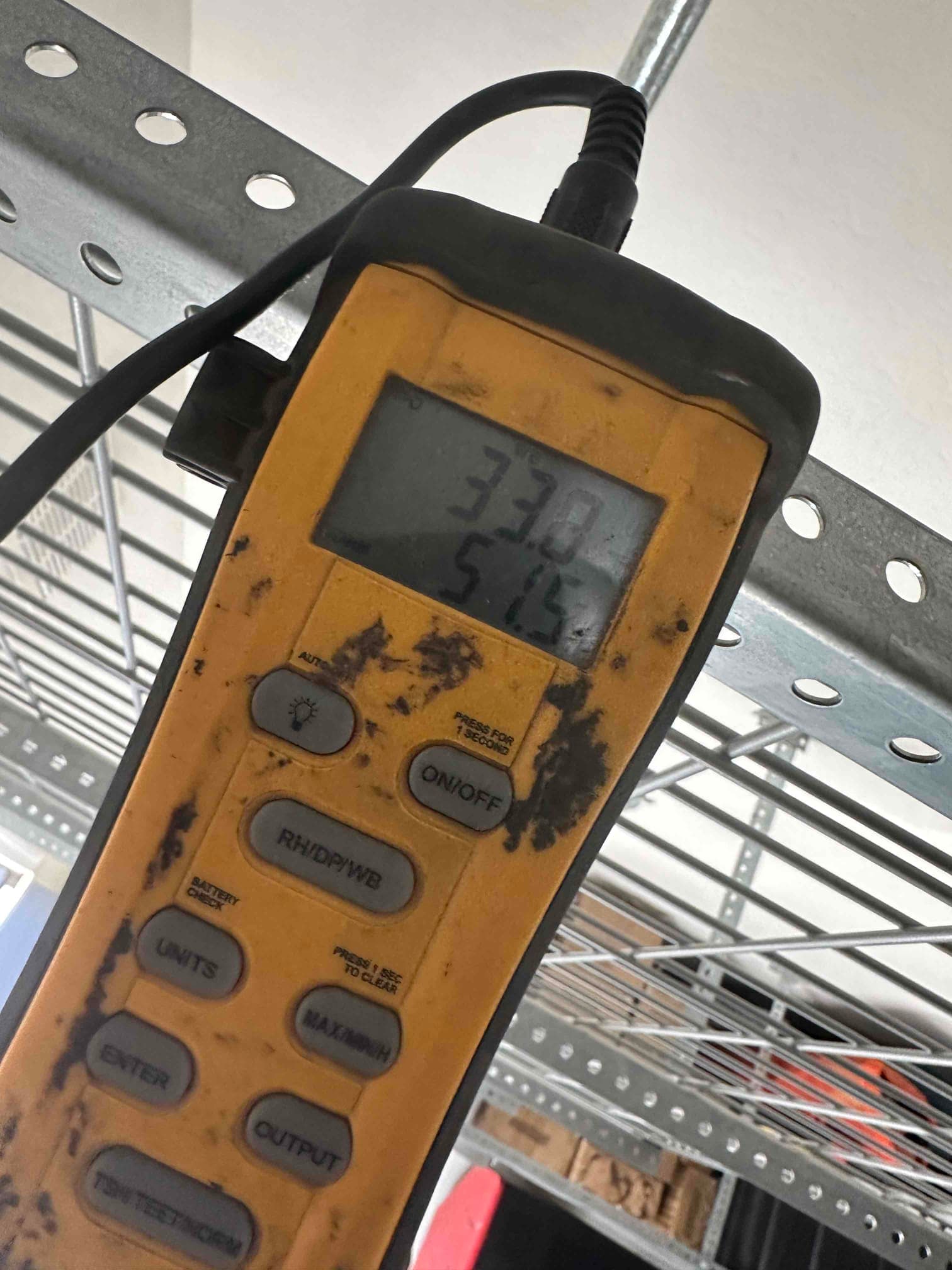 Digital thermometer probe displays 33.8 and 51.5 on the screen during air temperature checks at the new heat pump installation.