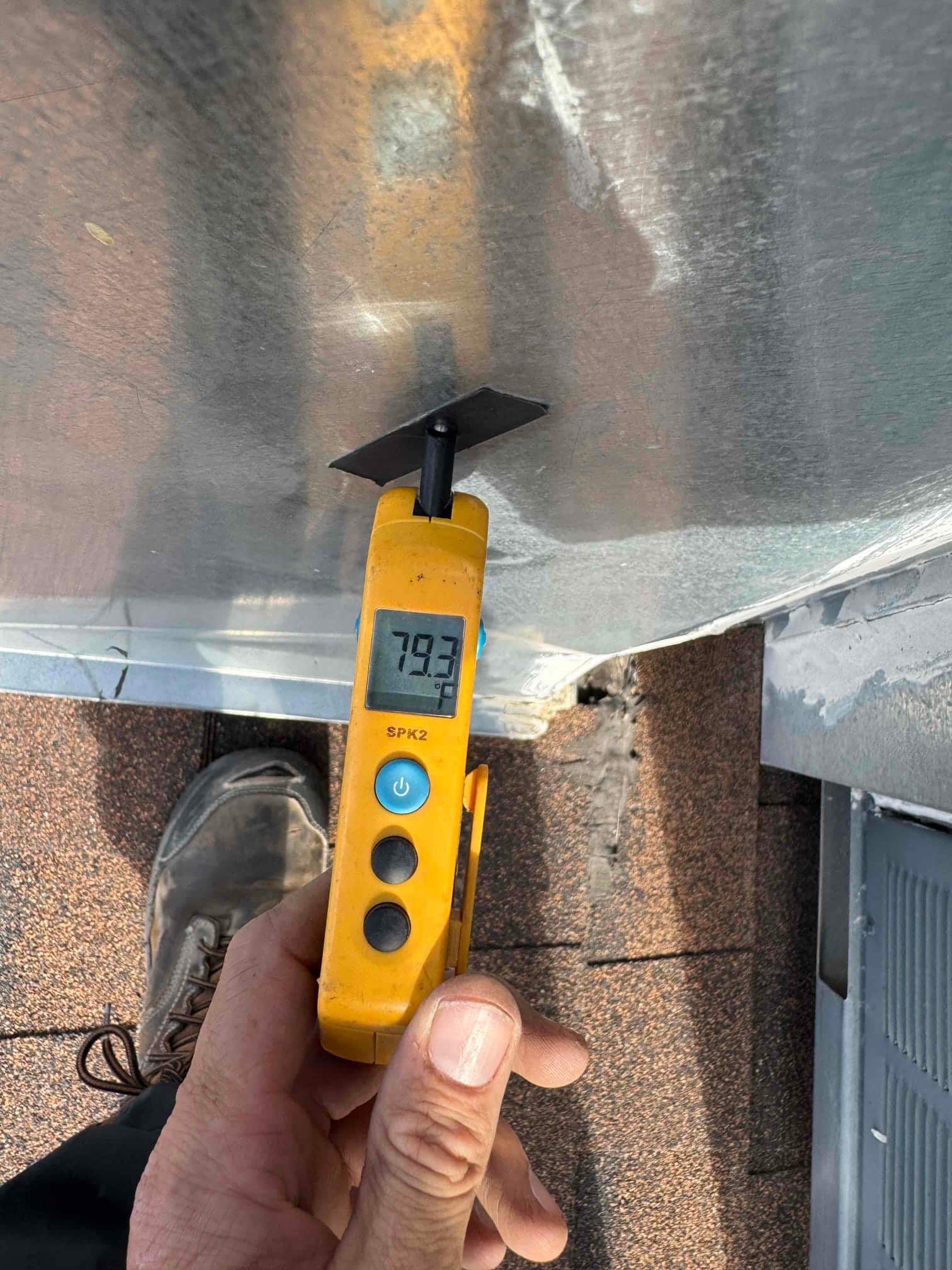 Digital thermometer probe measures surface temperature at 79.3 °F on the metal HVAC cabinet near the repair area.