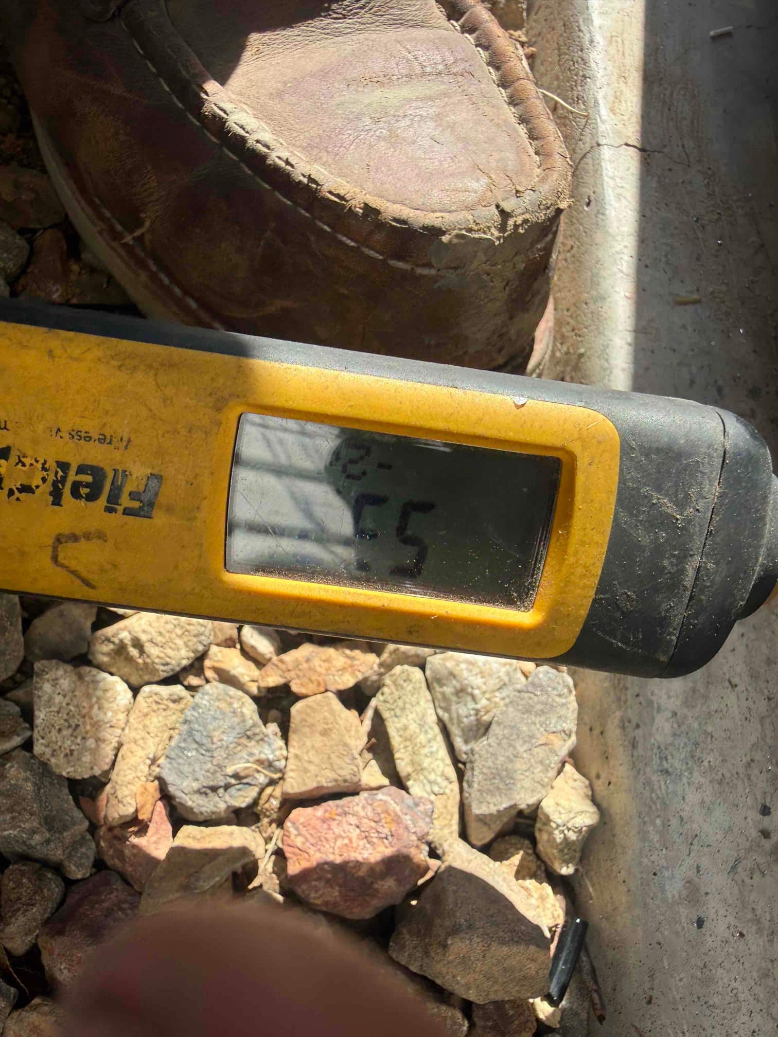 Digital thermometer probe shows a mid-70s reading outdoors, documenting return air temperature during commissioning.