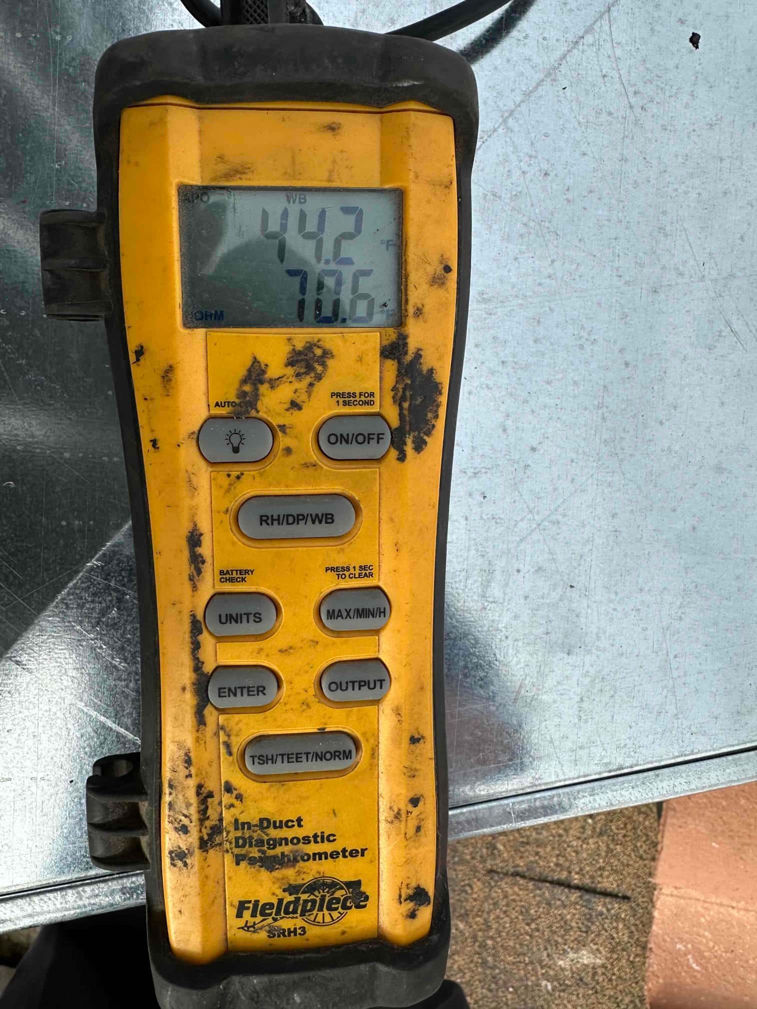Digital thermometer shows 70.6 degrees Fahrenheit during air-side measurements on the newly installed system.